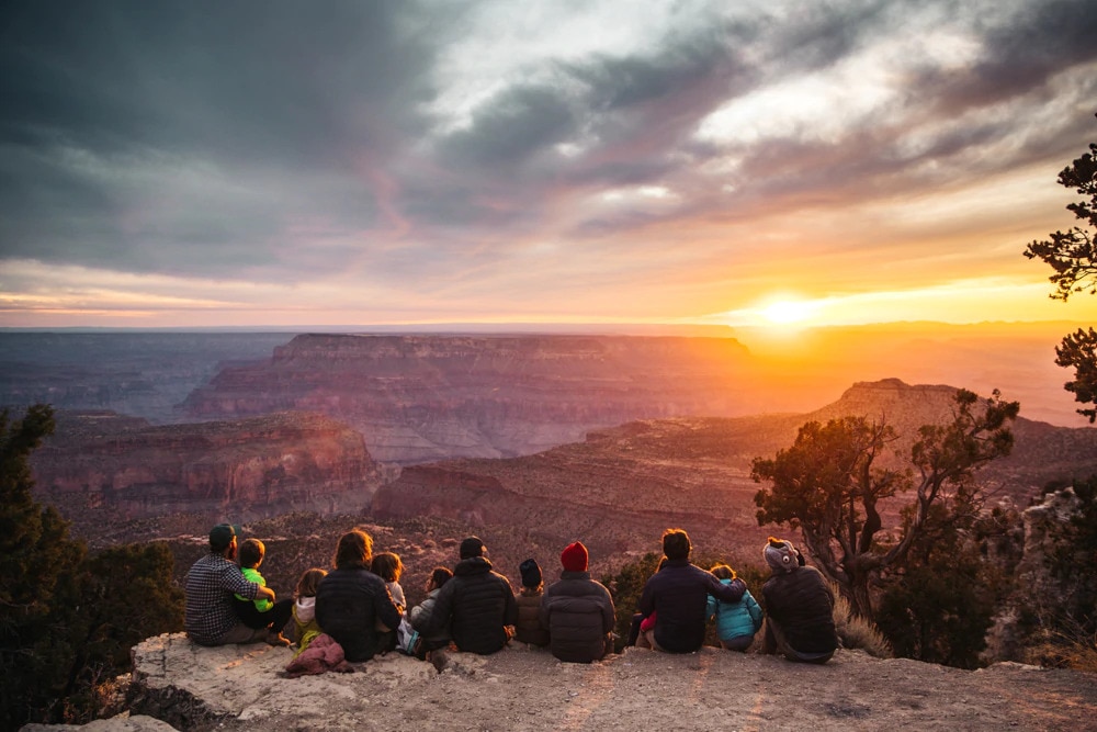 Des familles avec des enfants qui regardent un beau couché de soleil dans le Grand Canyon
