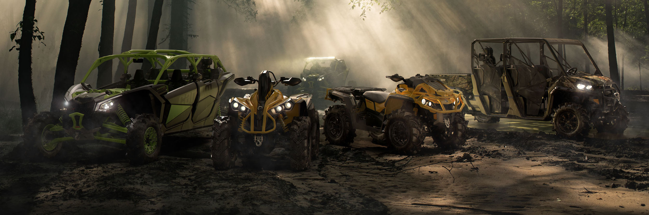 Two Can-Am ATVs and three Can-Am side-by-sides parked in a forest