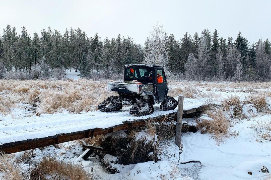 Rear view of a Can-Am Defender Limited with track system on a wooden bridge in winter