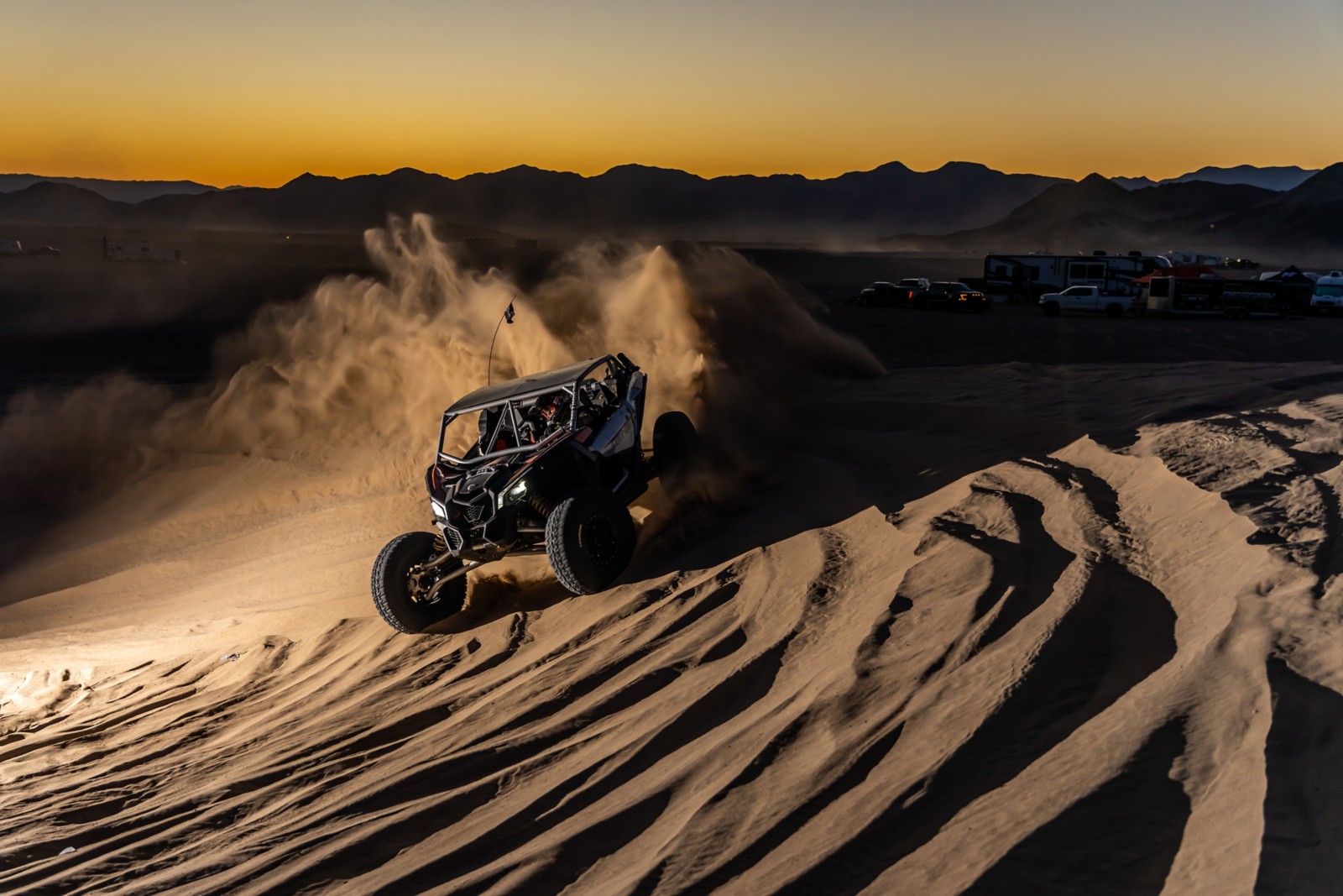 Conductor disfrutando de las dunas de arena por la noche, en un vehículo Can-Am Off-Road