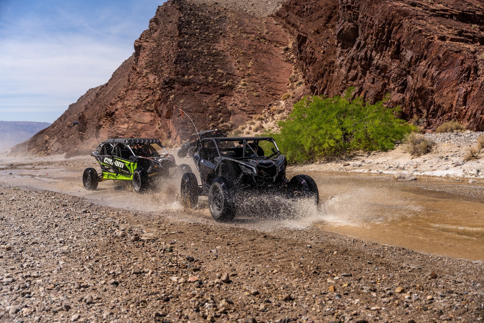 Two Can-Am SxS vehicles passing through water