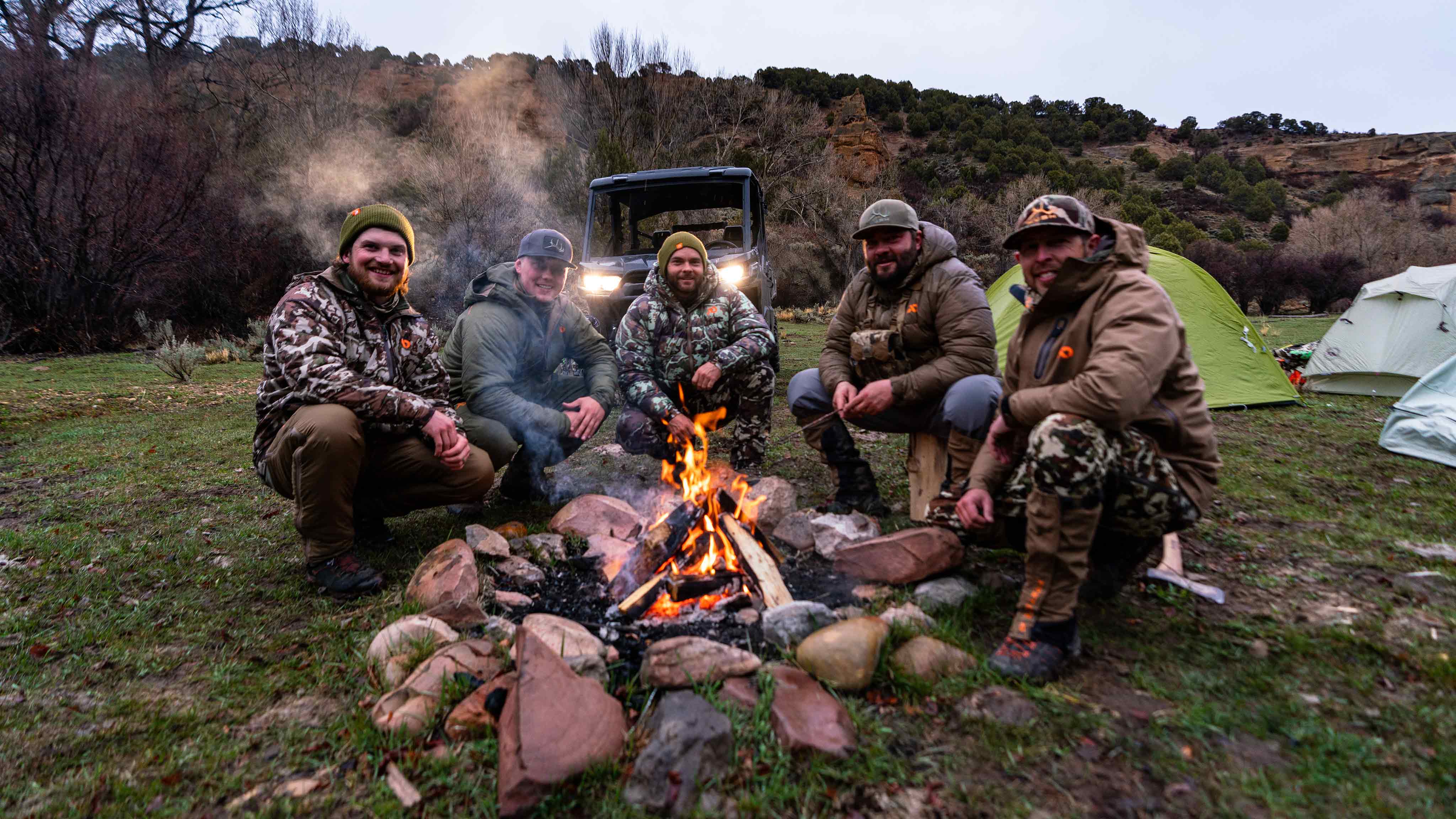 Cinco hombres están sentados junto al fuego