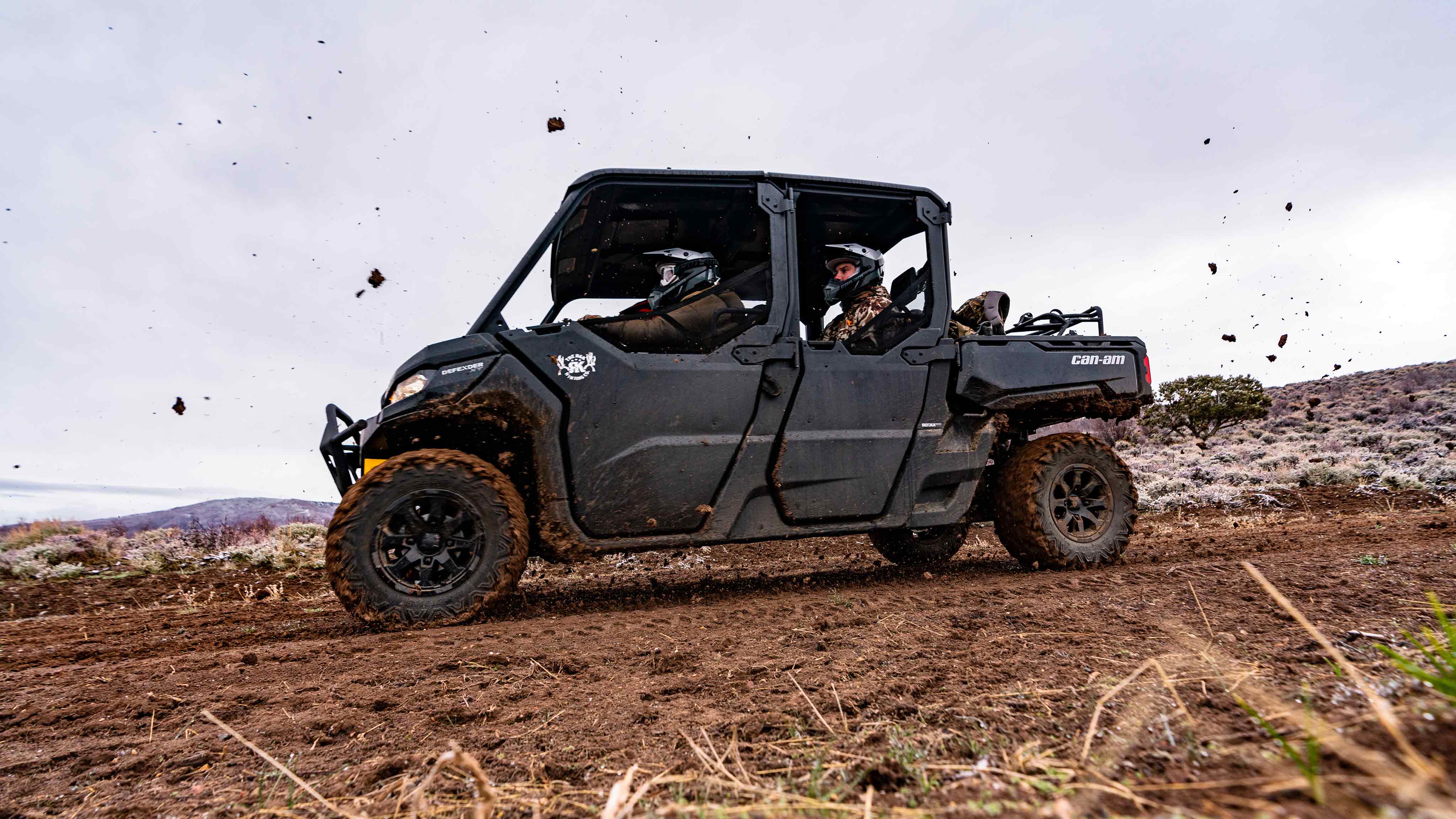 Two men riding inside a Can-Am Defender.