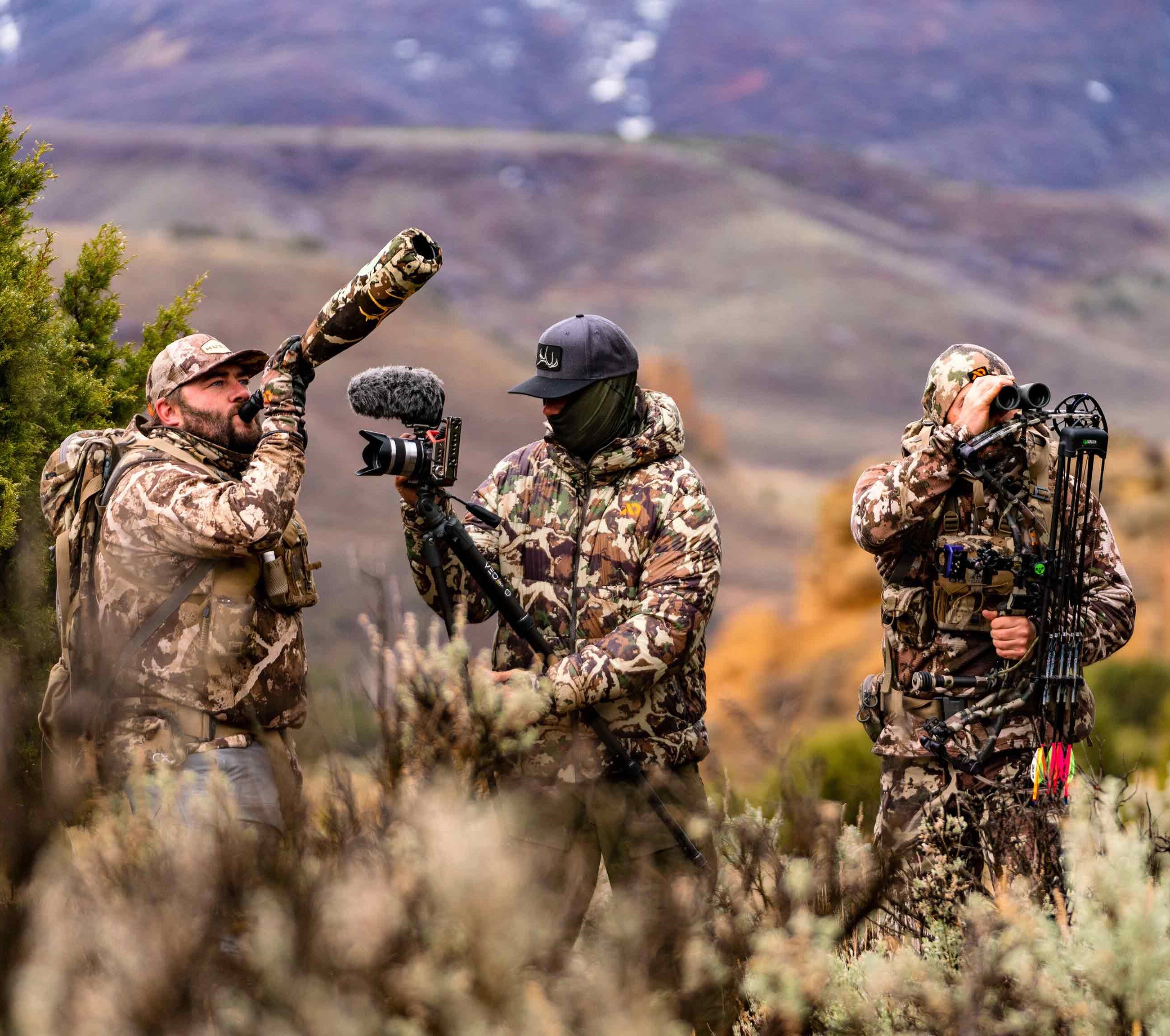 Three members of the Hushin' crew dressed in camo filming one of their members calling an animal. 