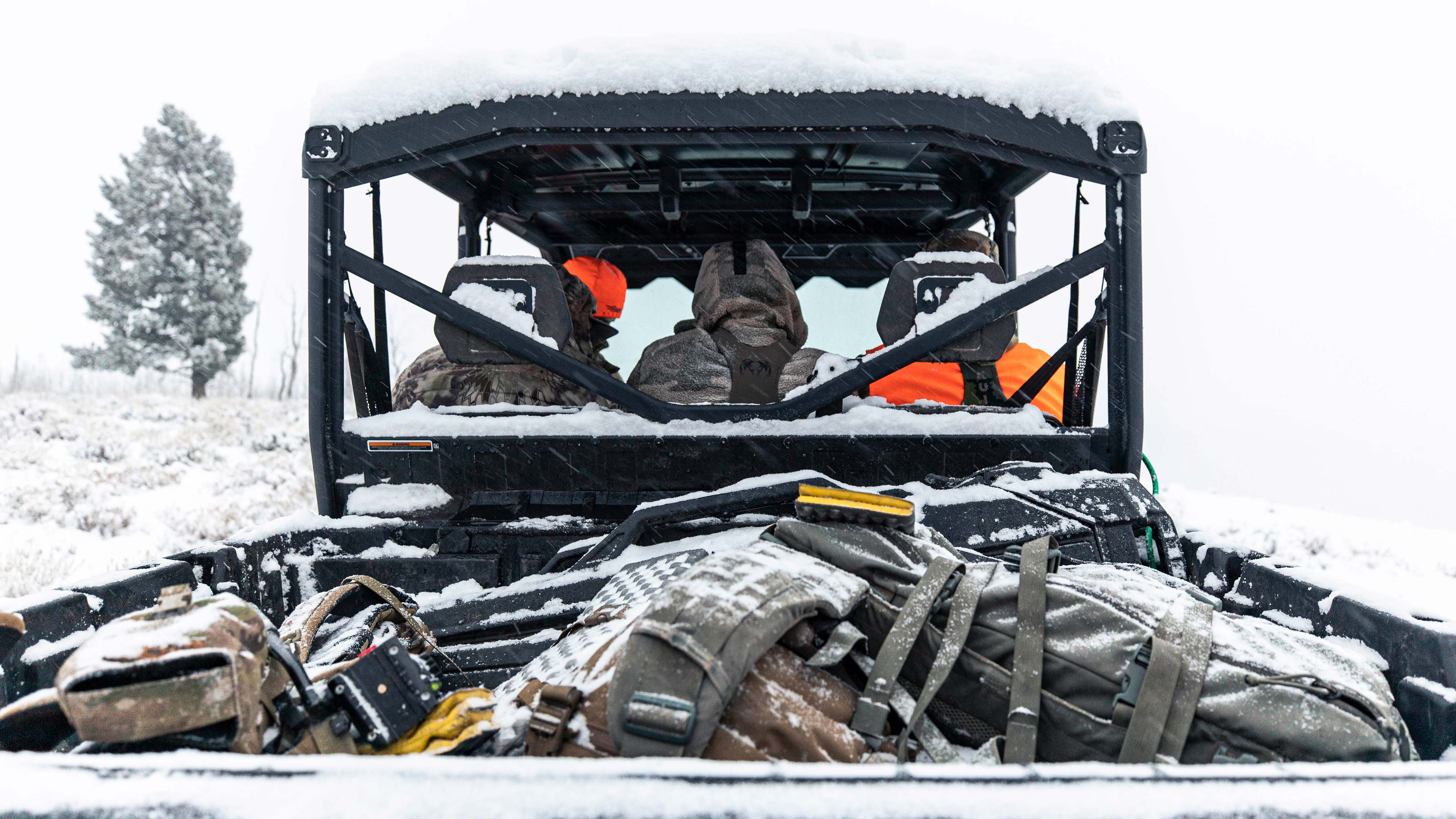 Three men inside snowy Can-Am Defender from rear
