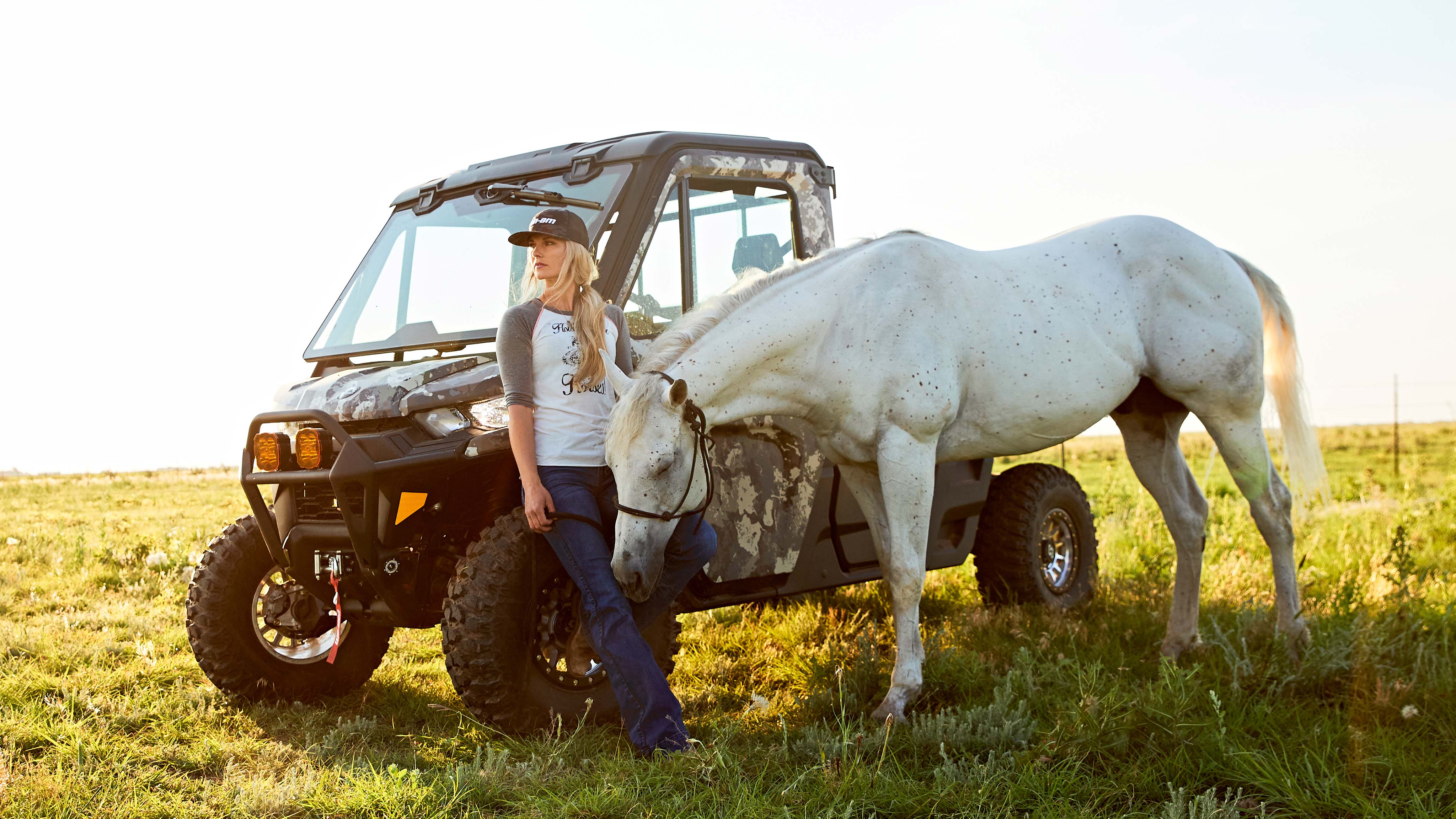 Kristy Lee Cook standing with her horse and Defender in a field, staring into the distance. 