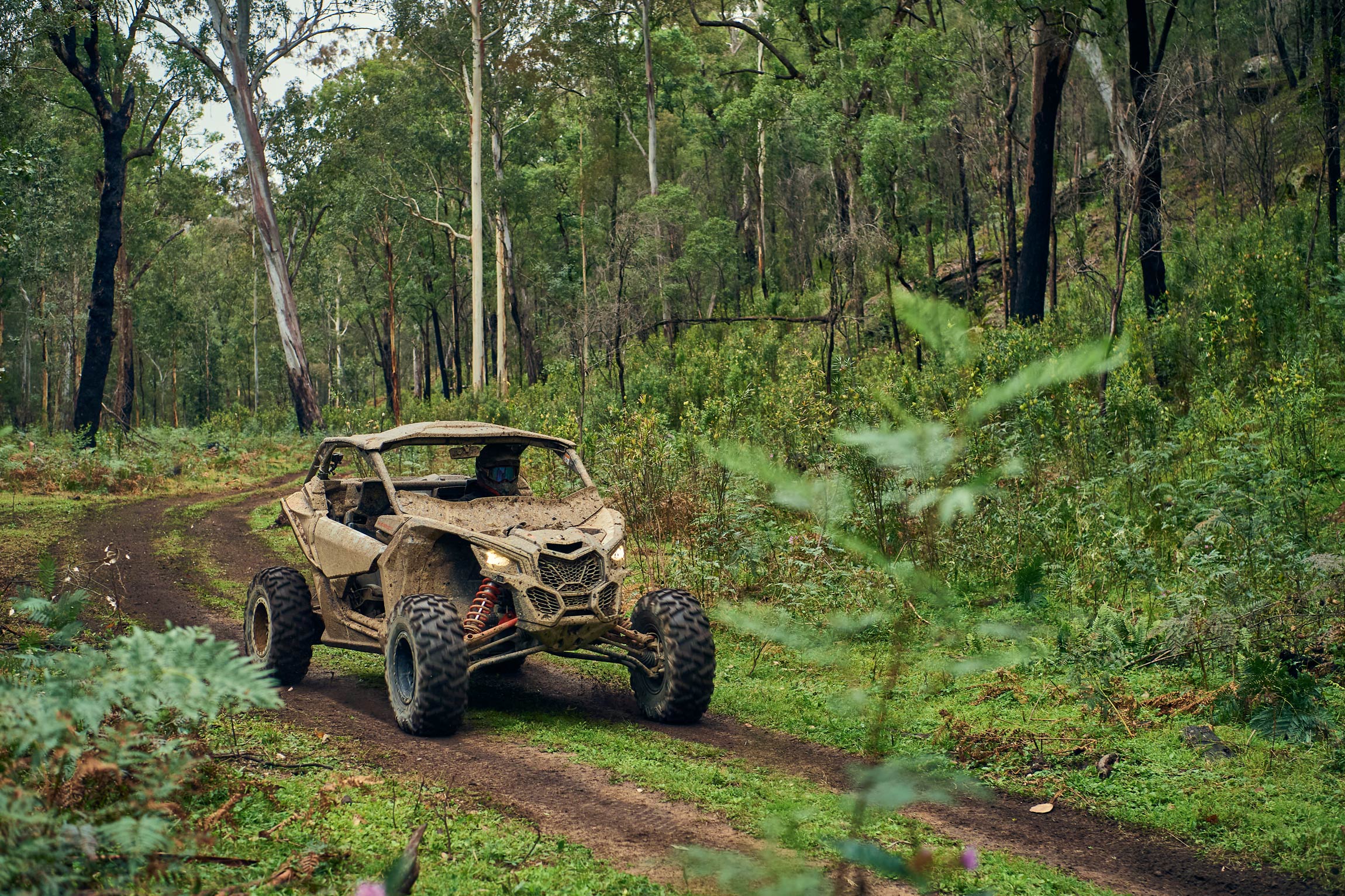 A side-by-side vehicle being driven on a muddy mountain trail