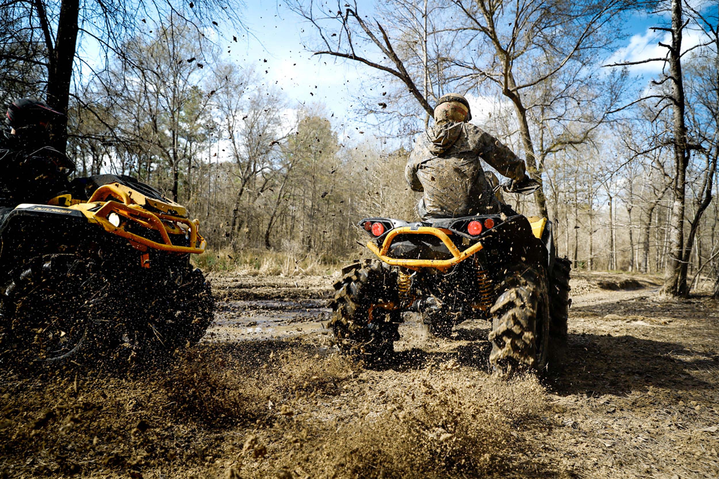 Two guys riding a Can-Am Off-Road ATV in the mud