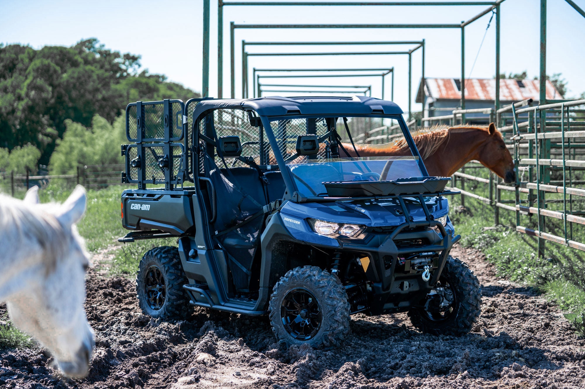 Un Can-Am Defender DPS personnalisé stationné dans un ranch avec des chevaux