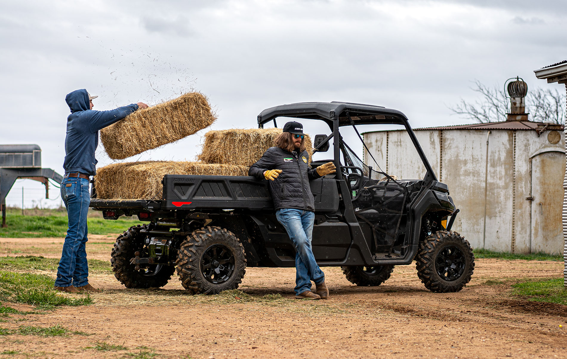 Man loads hay into Can-Am Defender PRO side-by-side while Dale Brisby relaxes