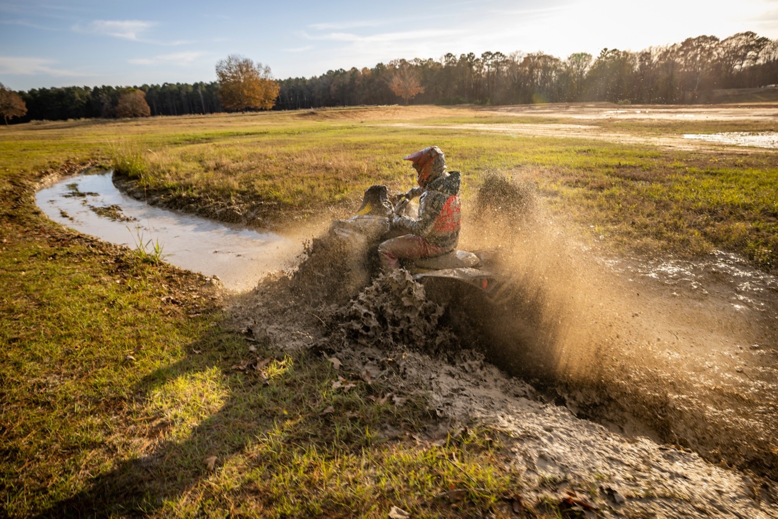 Osta Cruiser riding through a muddy field on his Can-Am ATV