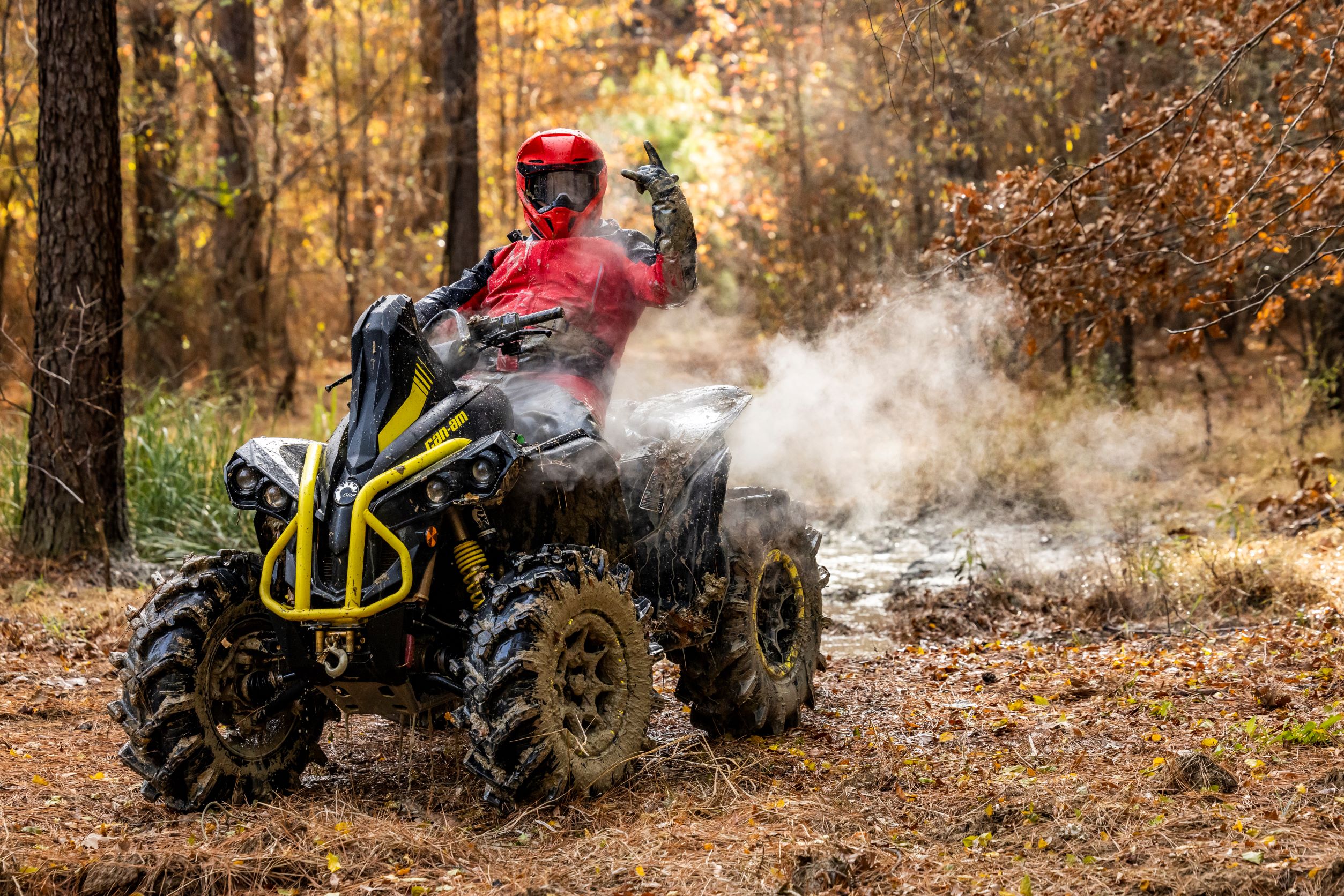 Can-Am rider posing on his Renegade X MR after a muddy ride, while steam rises from the vehicle. 