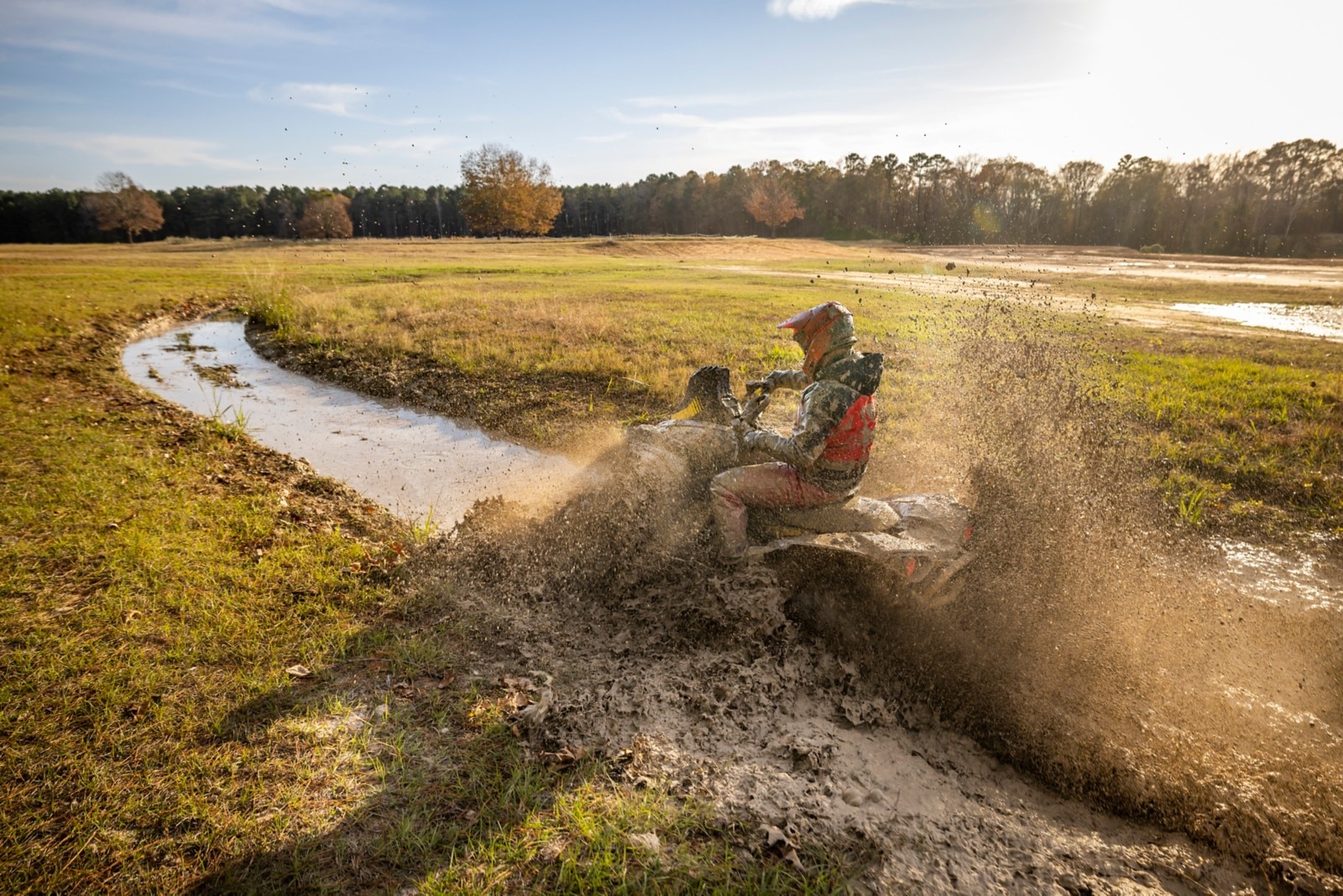Osta Cruiser roulant à travers un profond trou de boue avec le soleil qui brille sur le terrain en arrière-plan.