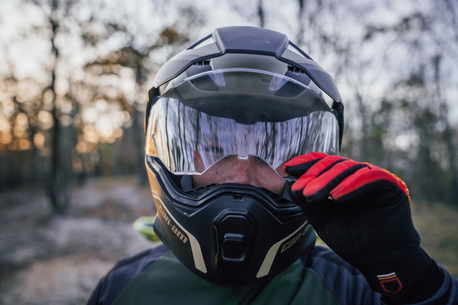 Close-up van een motorrijder die het vizier van zijn Can-Am Exome-helm opent