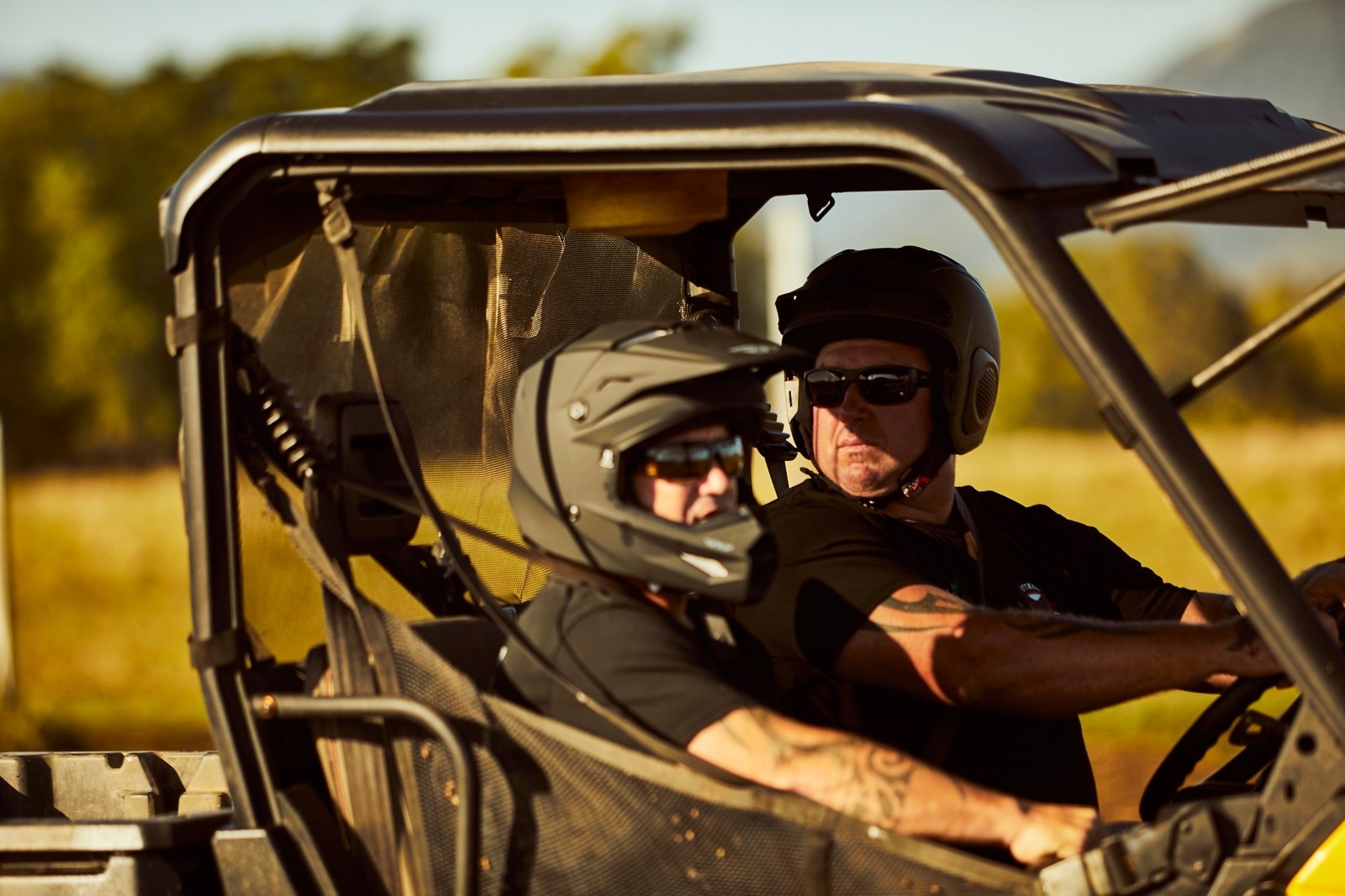 Jason Dittman driving his Can-Am Defender with a passenger, looking back over his right shoulder