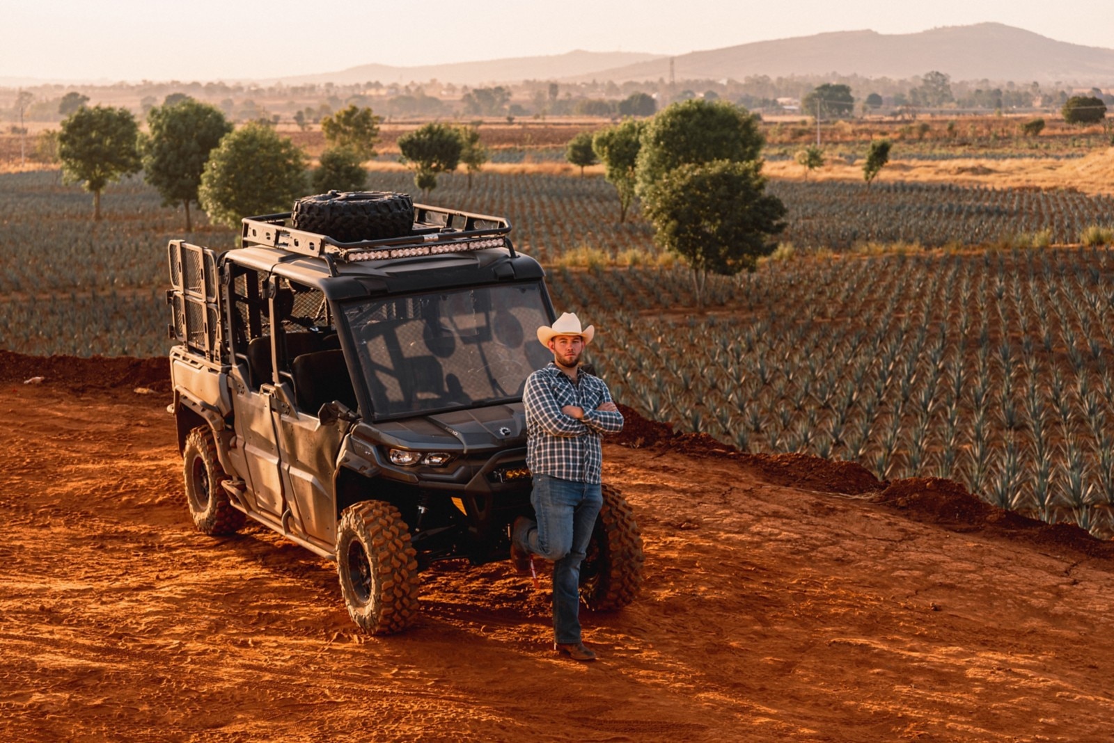 One of the Trujillos standing in front of their Defender with an agave field in the background. 
