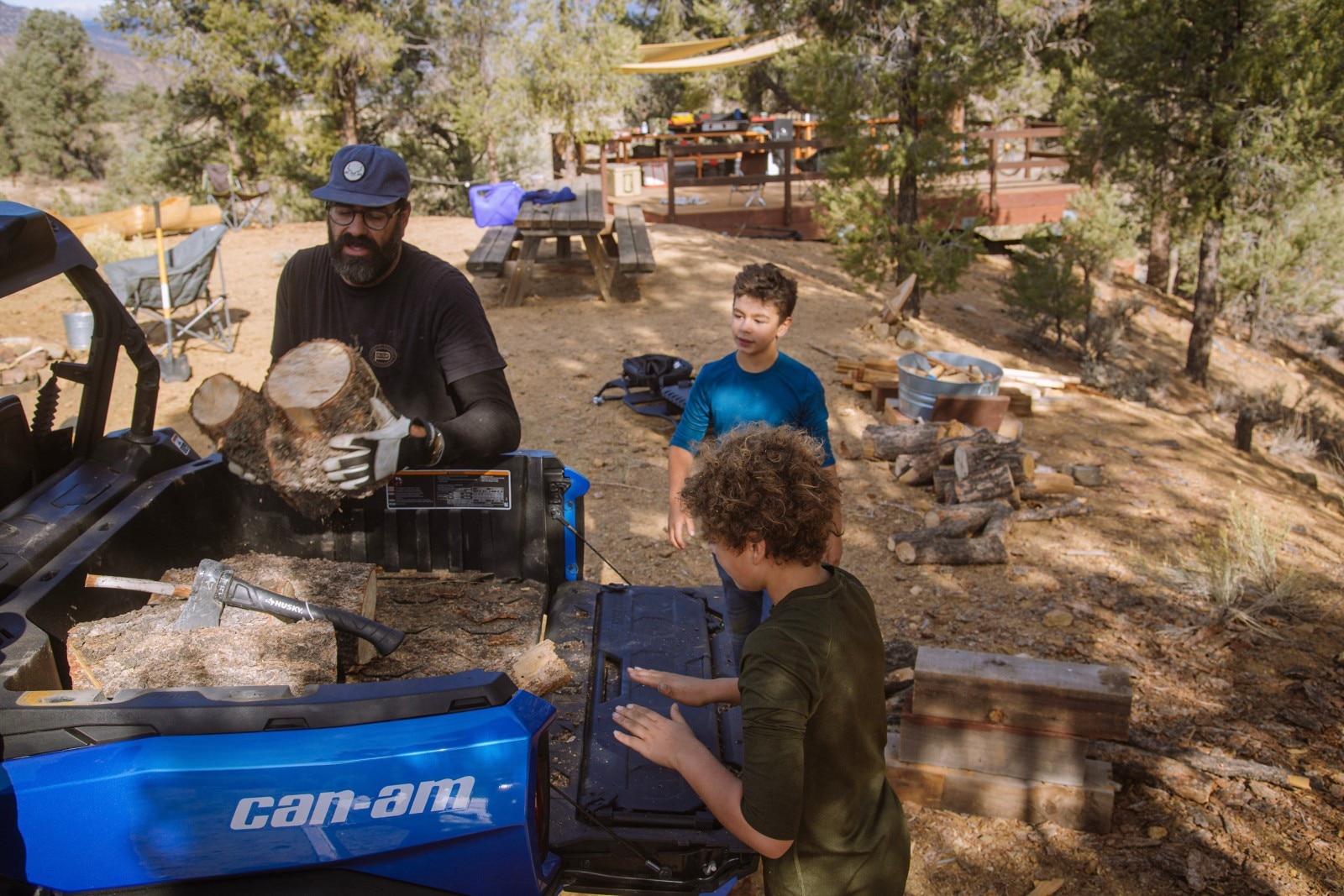 The three Parks' boys loading wood log sections into the bed of their Oxford Blue Can-Am Commander MAX XT.