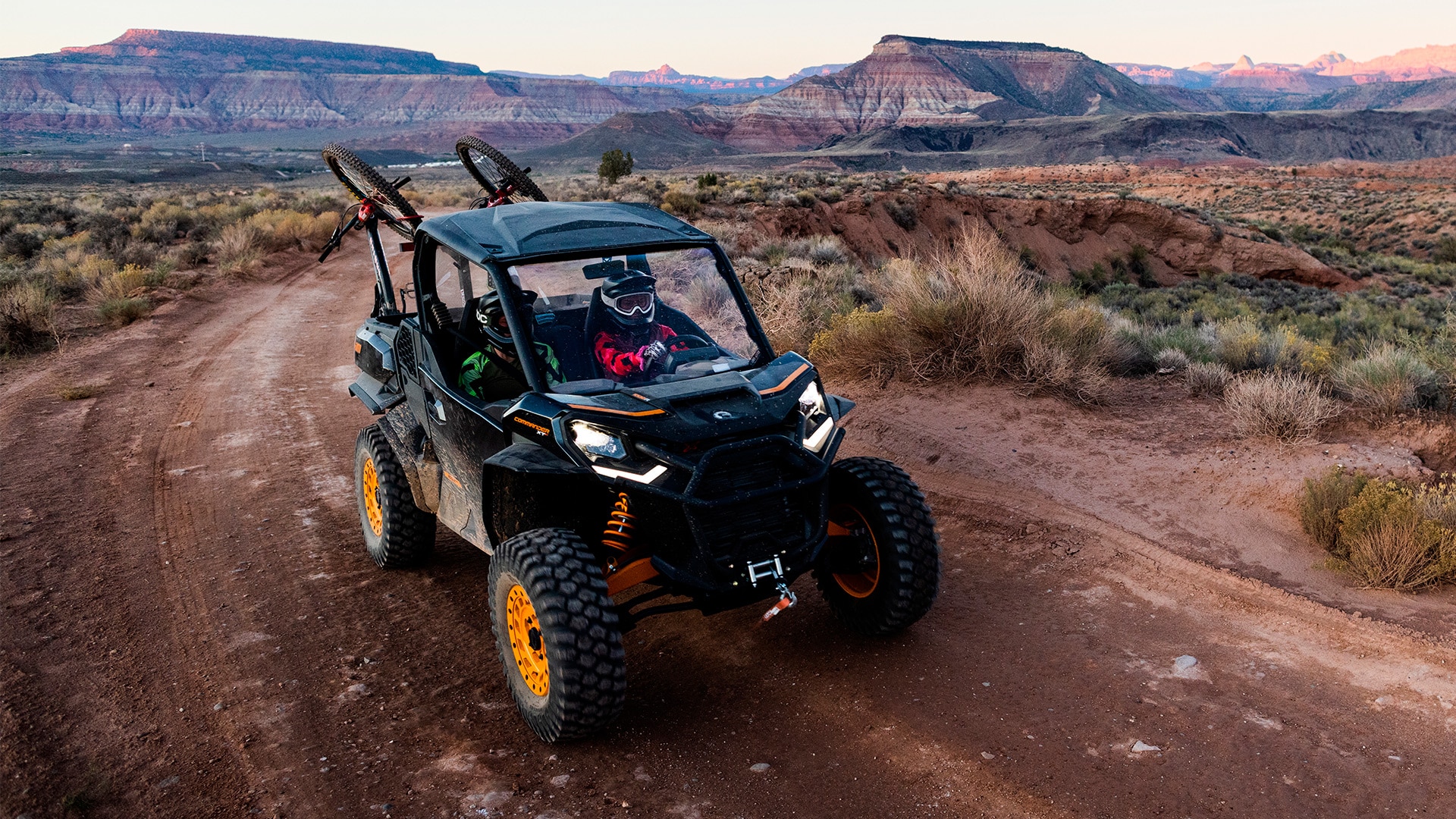 Samantha Soriano wearing a Can-Am helmet and driving the Can-Am Commander with orange trims on a trail