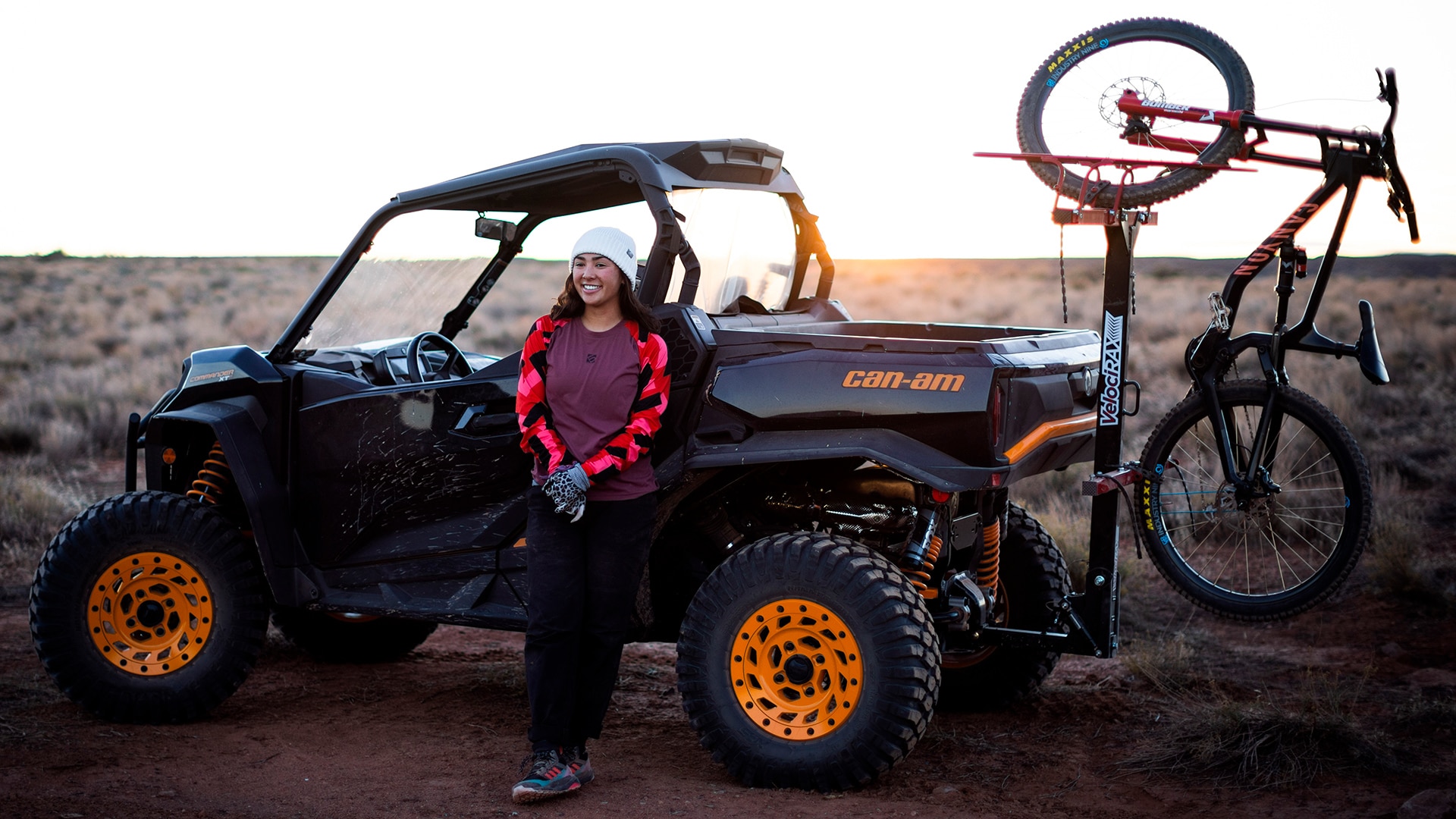 Samantha Soriano leaning back on a black Can-Am Commander with orange trims and smiling for the camera