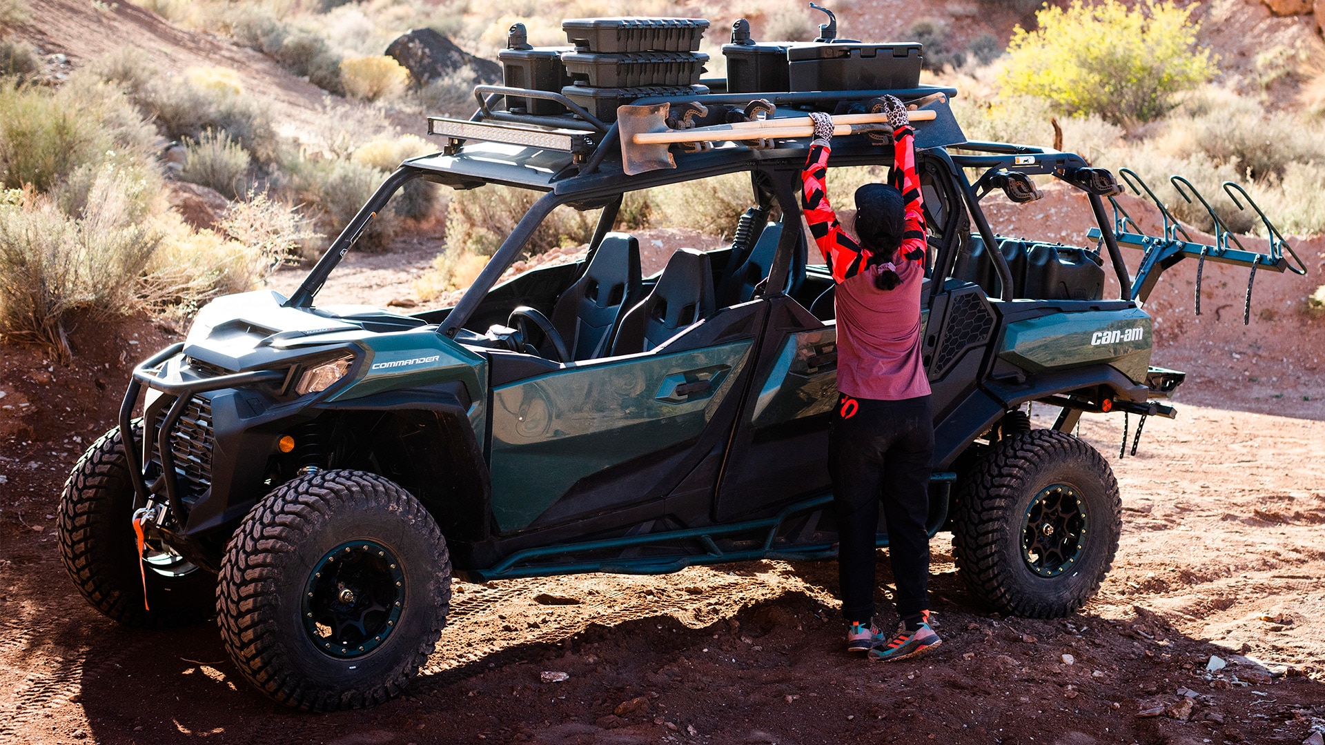 Samantha Soriano placing a shovel securely on the Can-Am Commander she has been riding outdoors on a trai