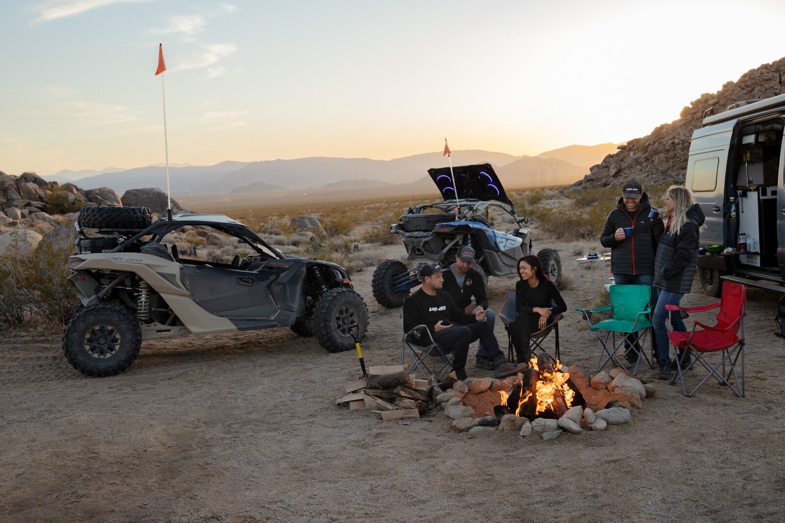 Can-Am Riders enjoying a campfire after a day of riding, with their Maverick X3s in the background