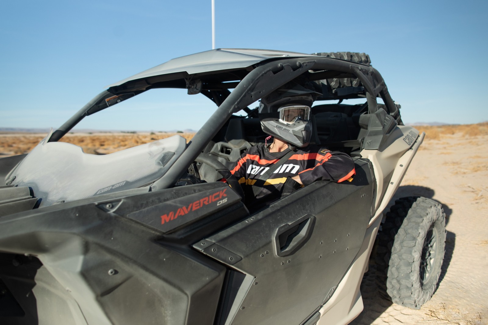 Close-up on a driver behind the wheel of a Can-Am Maverick X3, wearing a Pyra helmet