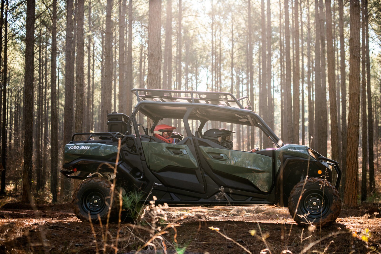 Side view of a Can-Am Commander MAX while the sun shines through the trees in the background