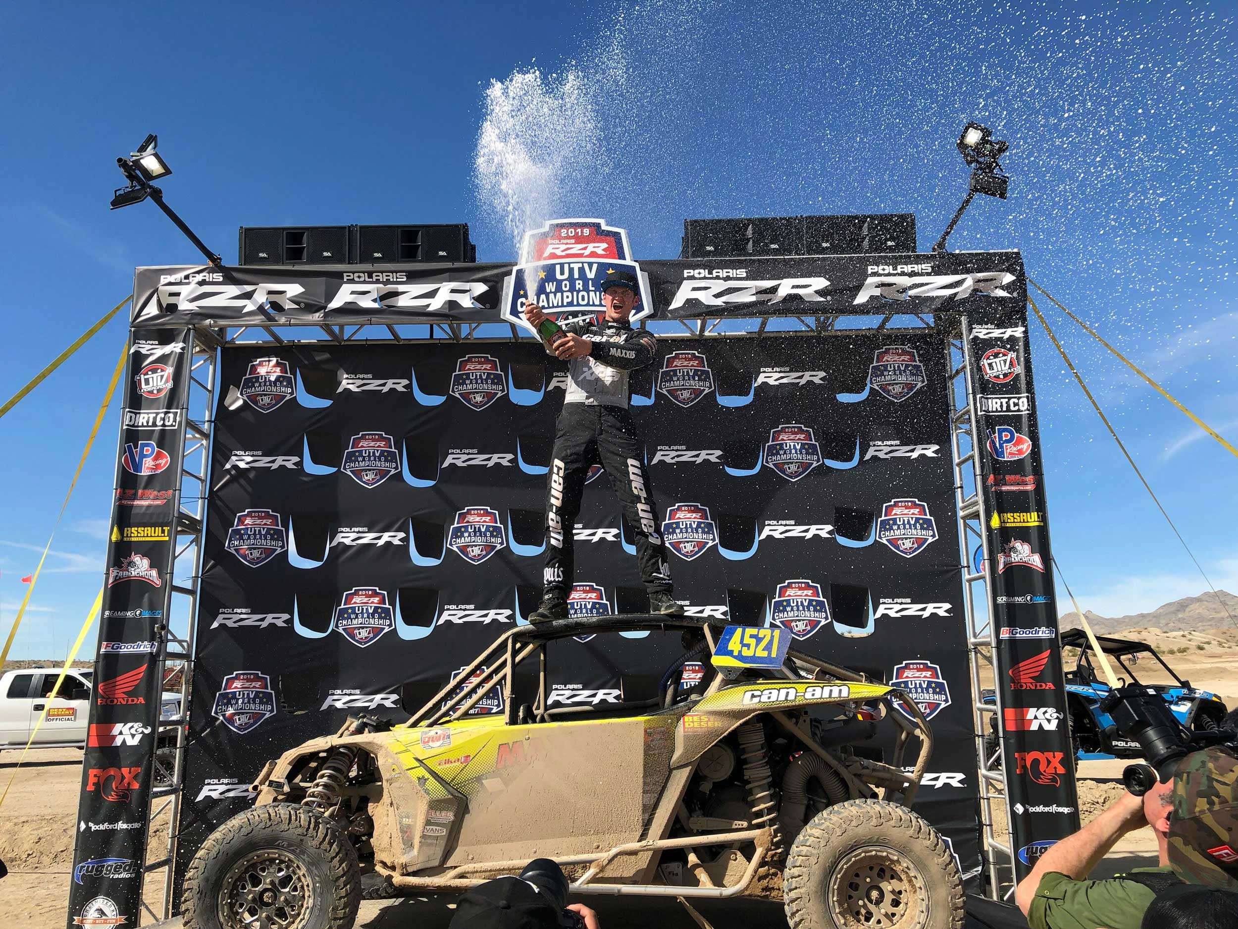 Cody Miller popping champagne standing on a Can-Am Maverick X3 side-by-side