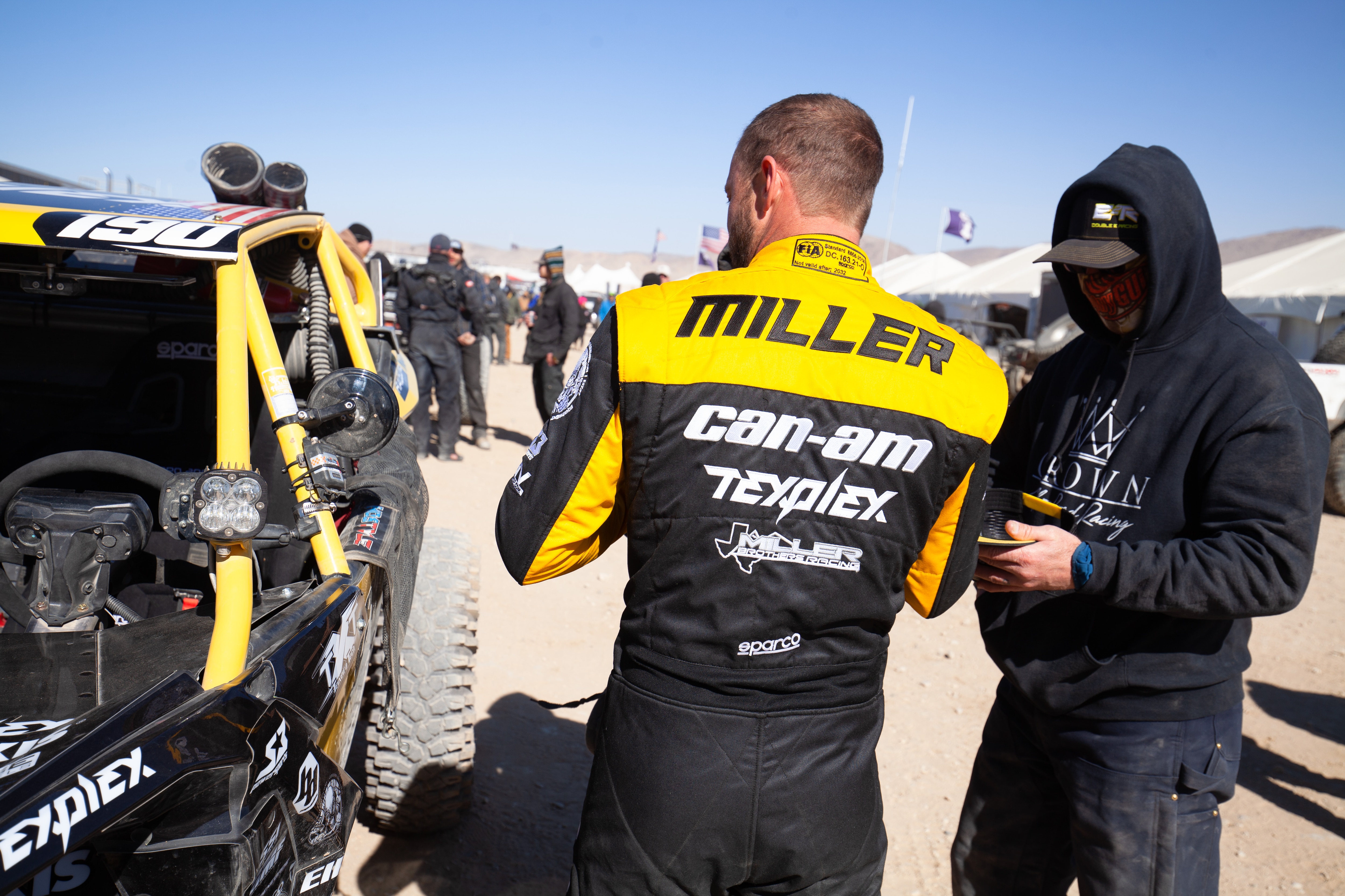 Hunter Miller standing outside his Maverick X3 during KOH, wearing his racing jacket with his name across the back.