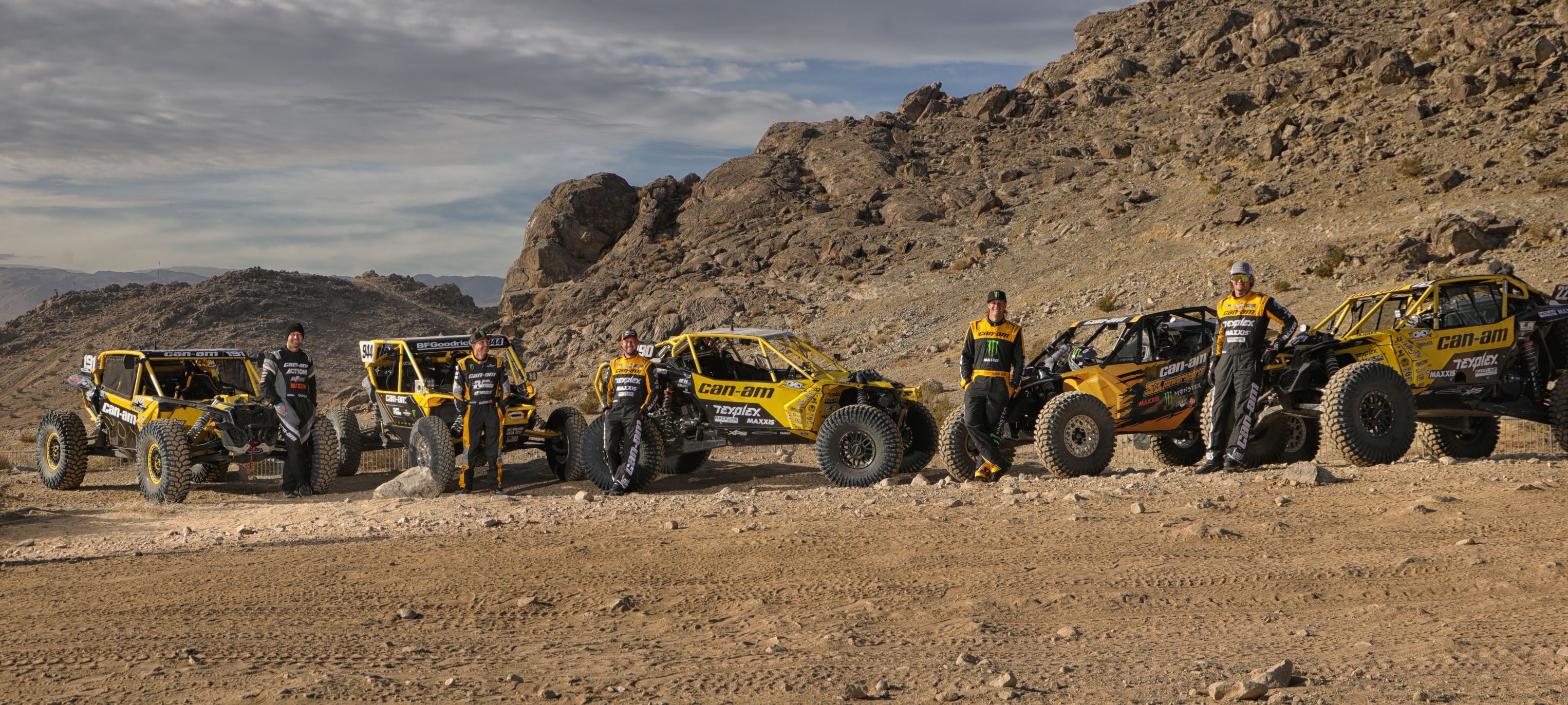 Los pilotos del equipo Can-Am amarillo frente a sus vehículos estacionados durante la carrera KOH