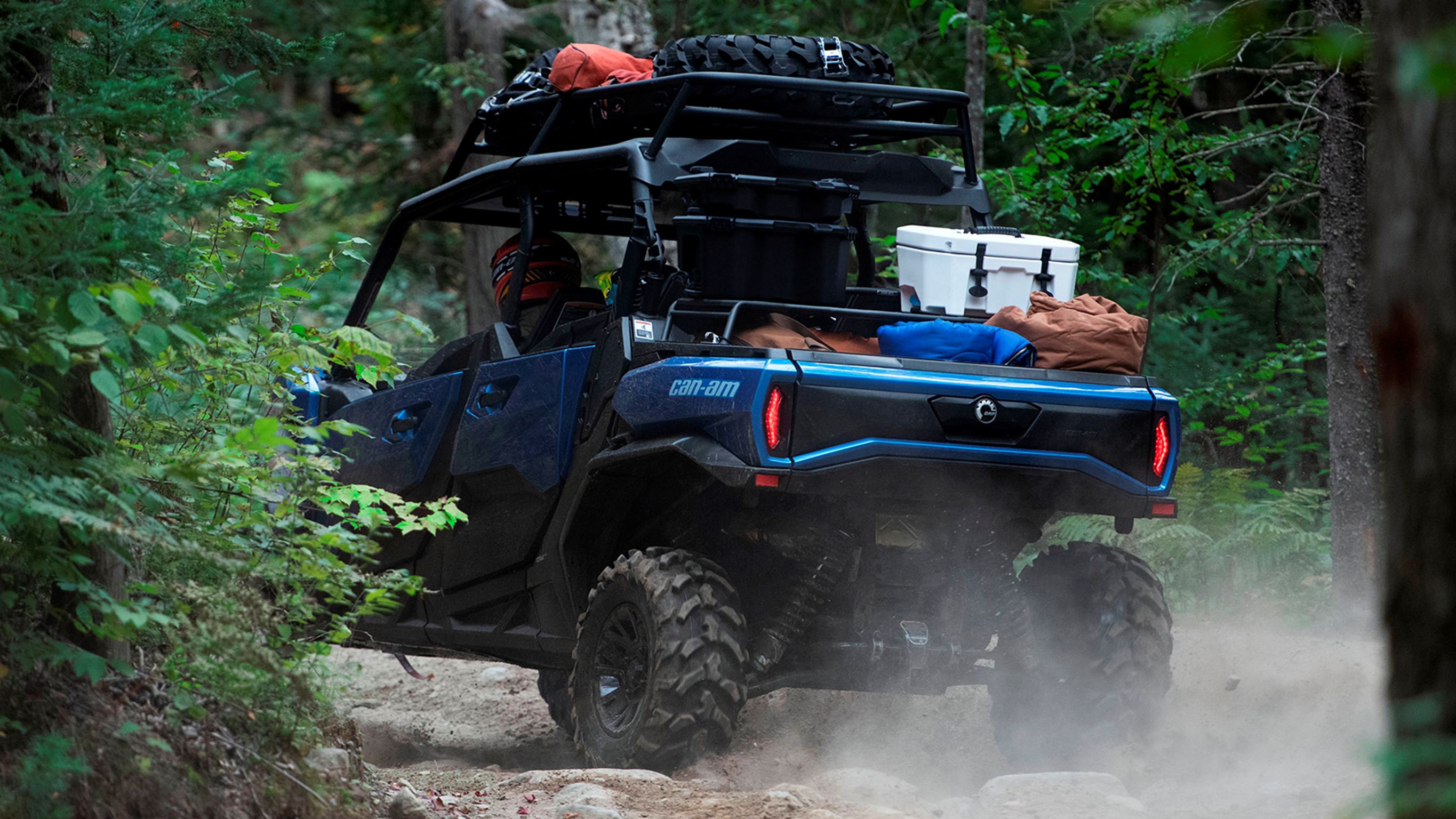 A 3/4 rear view of an Oxford Blue Can-Am Commander MAX XT loaded with aventure gear on a trail.