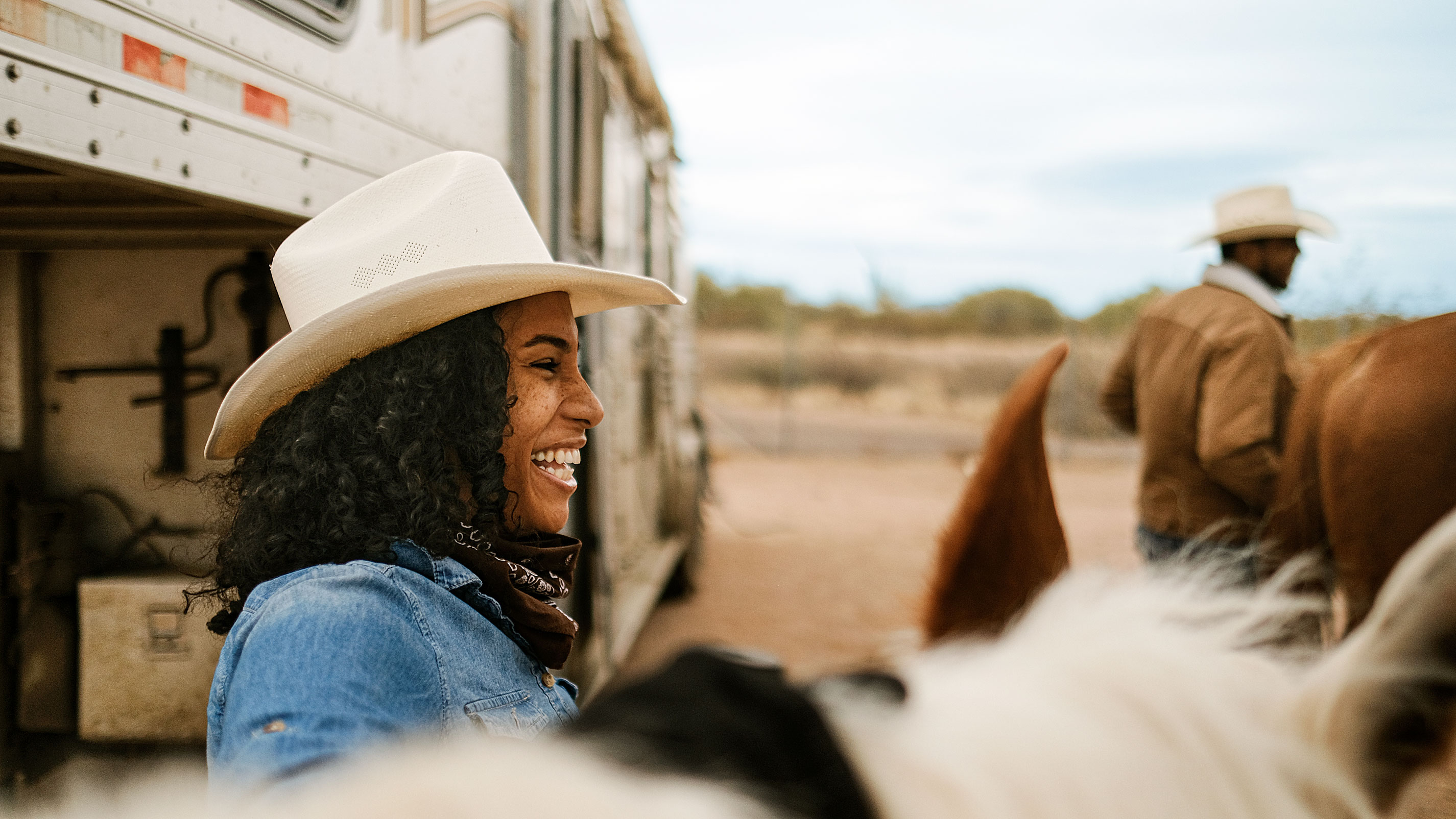 A cowgirl smiling next to horses