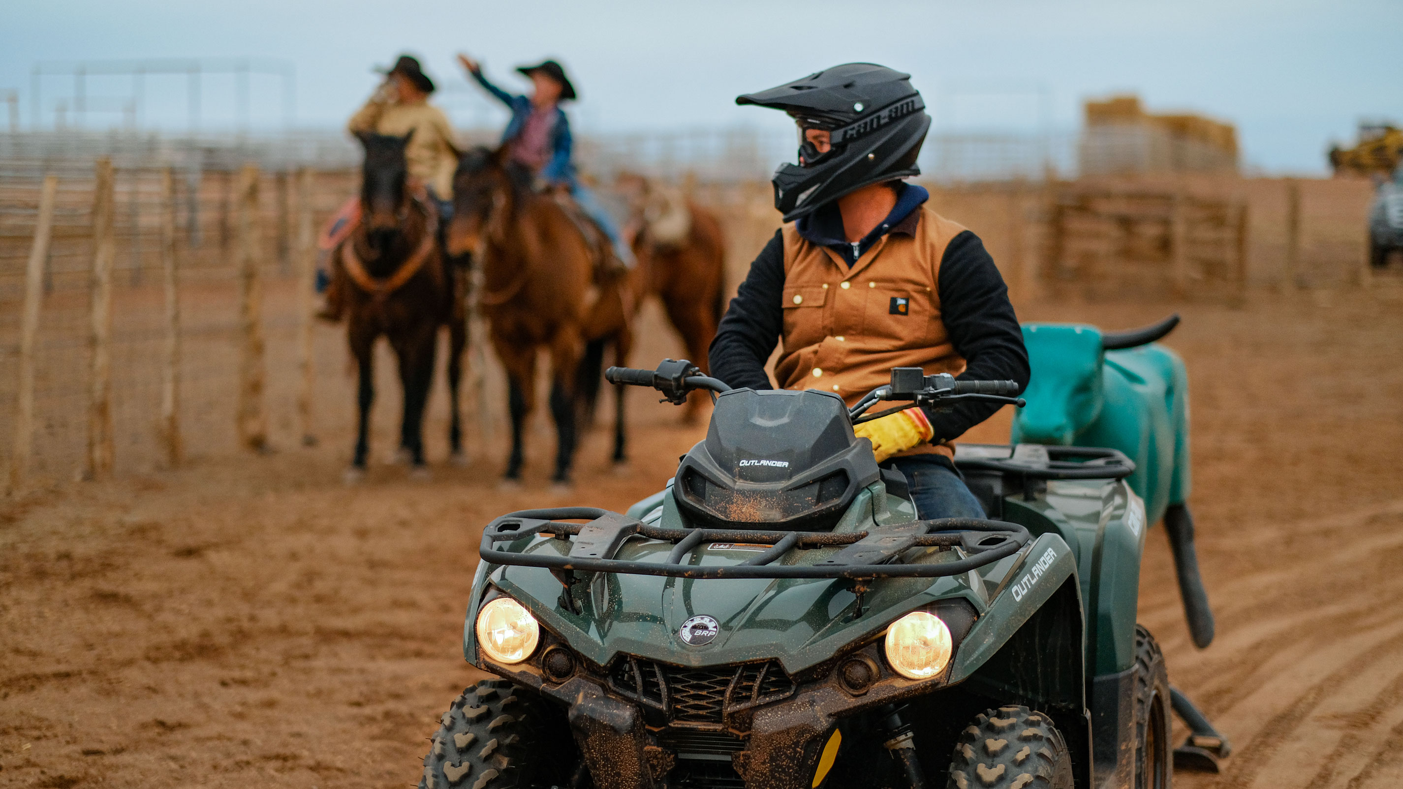 Un homme dans un VTT près de cowboys dans un ranch