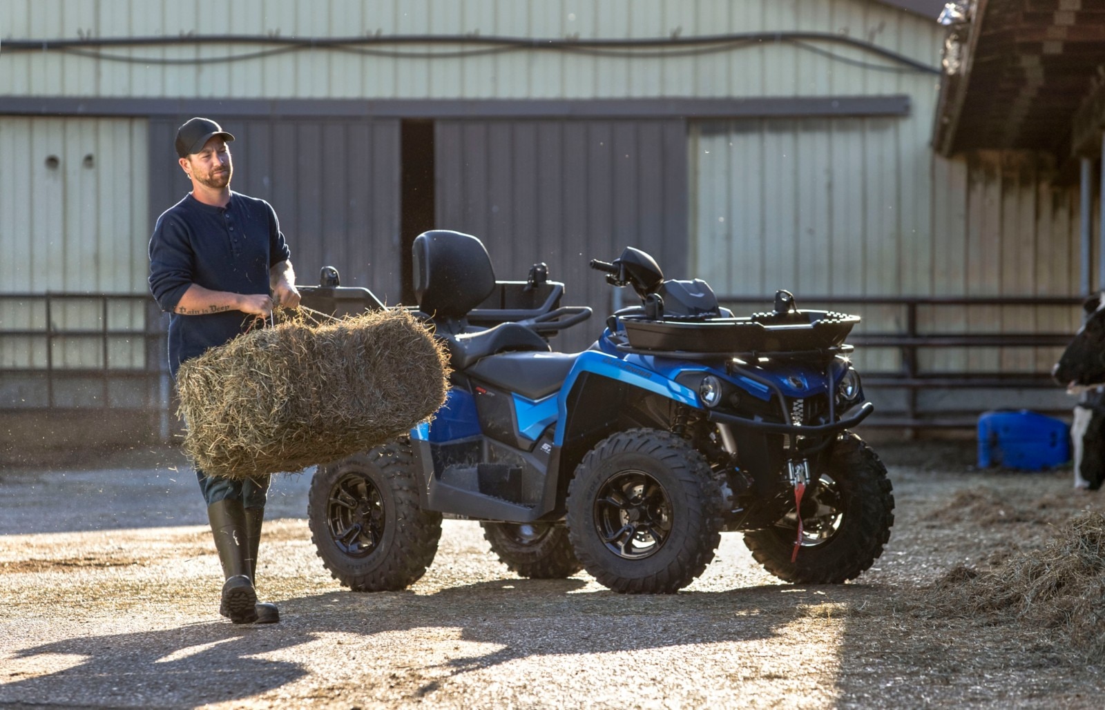 A farmer holding a bale of hay in front of Can-Am ATV