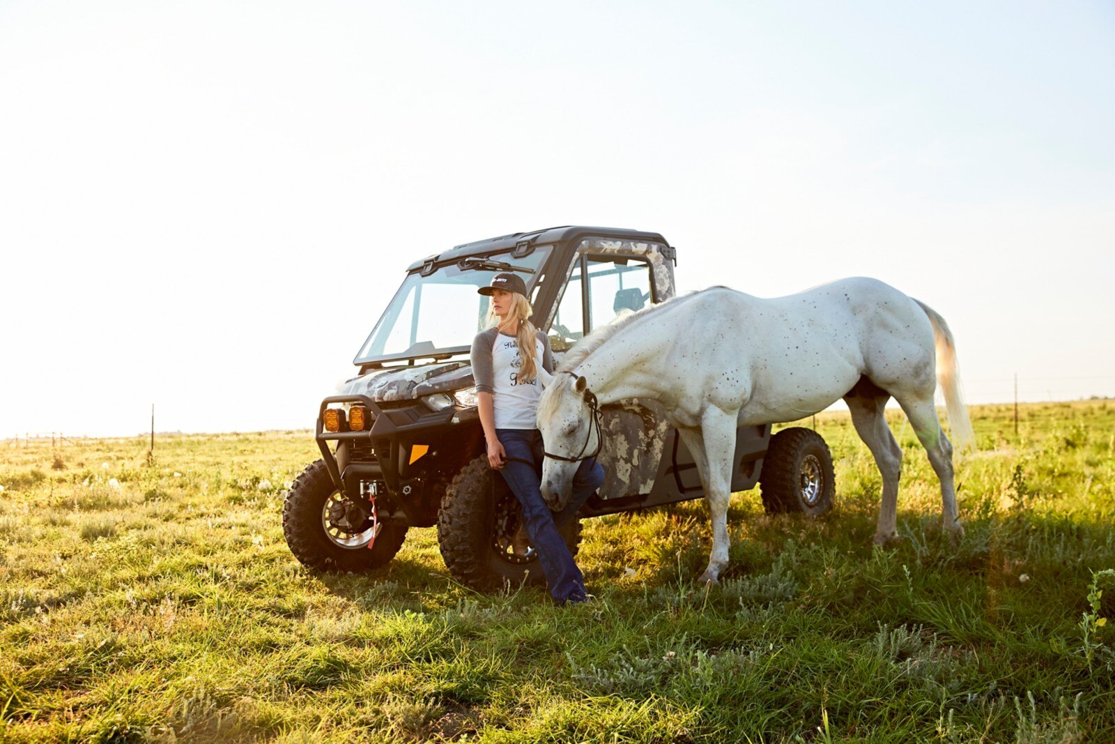 Kristy Lee Cook standing with her horse and Defender in a field, staring into the distance. 