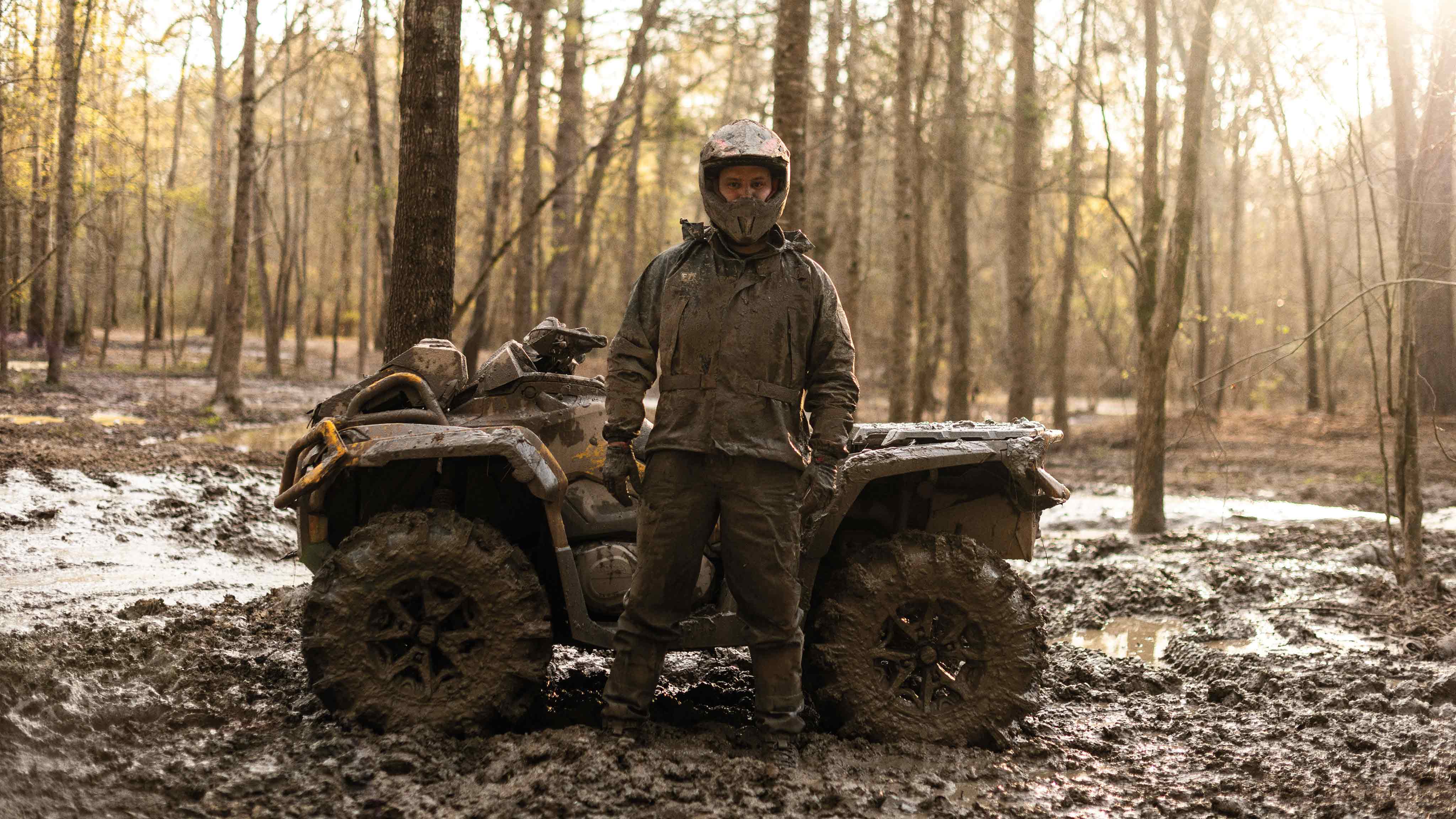 Man och Can-Am-ATV täckta av lera 