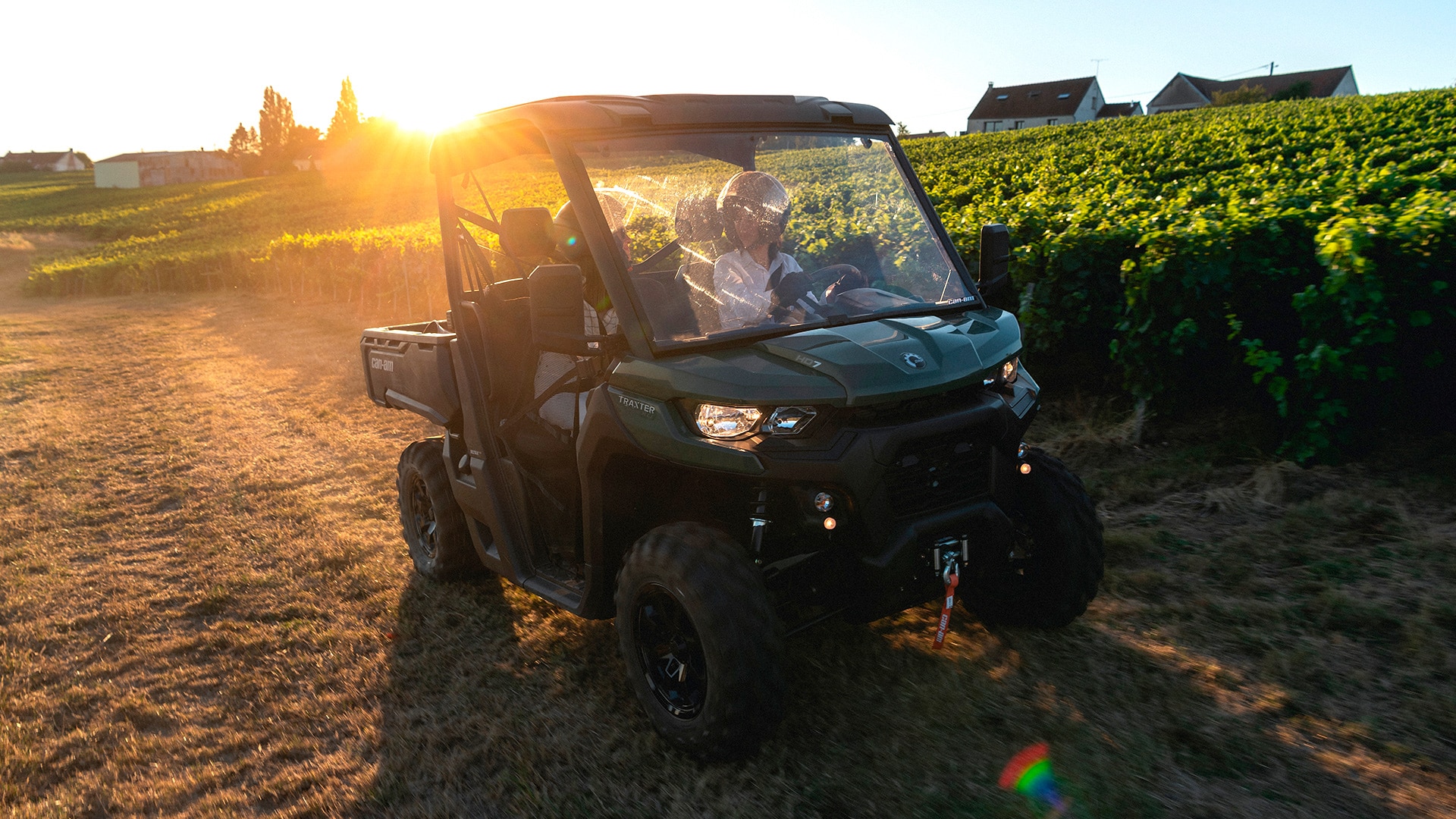 Riders riding a Can-Am Defender SxS on the vineyard