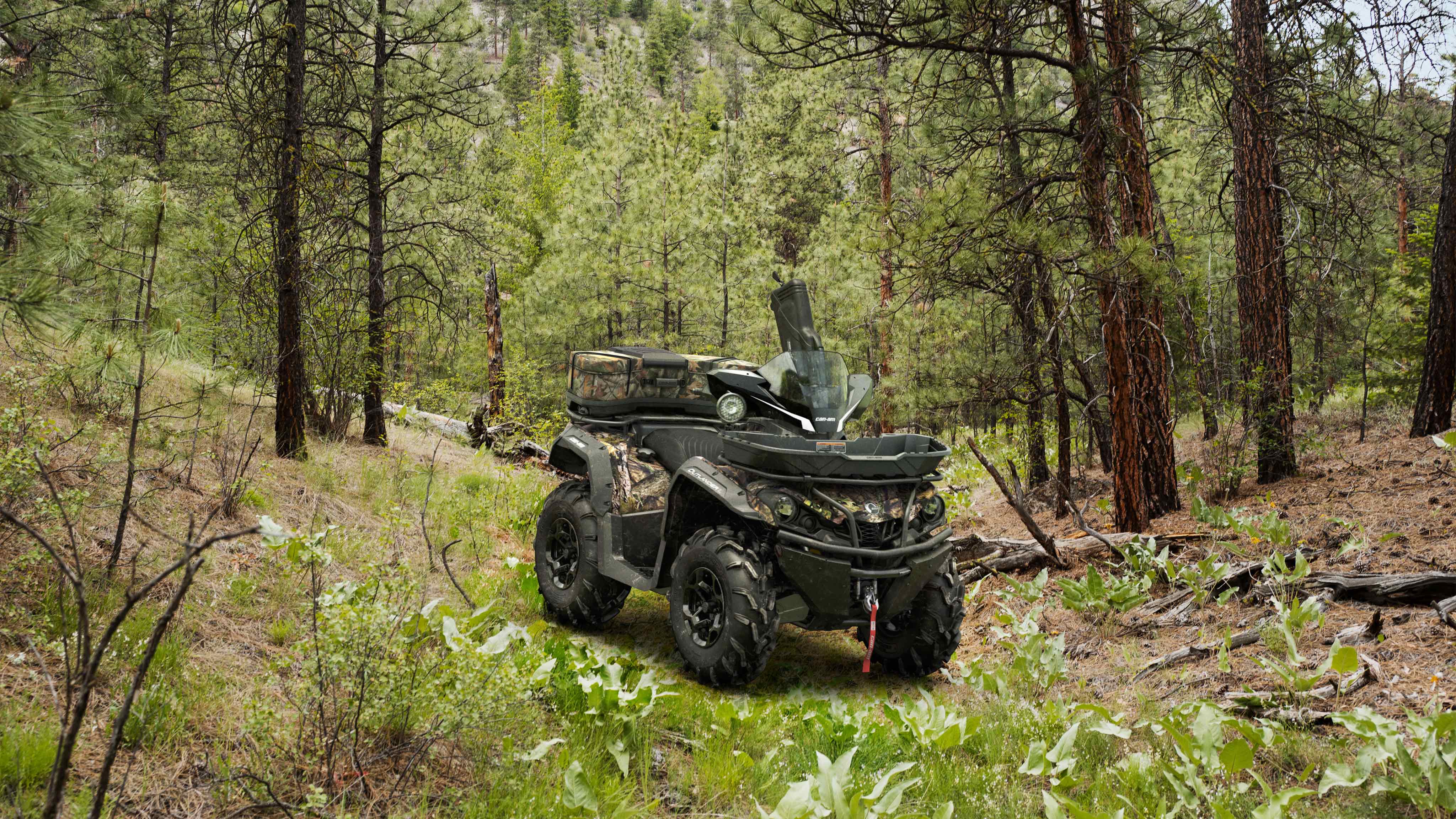 Un Outlander de color roble musgoso aparcado en el bosque con equipo de caza. 