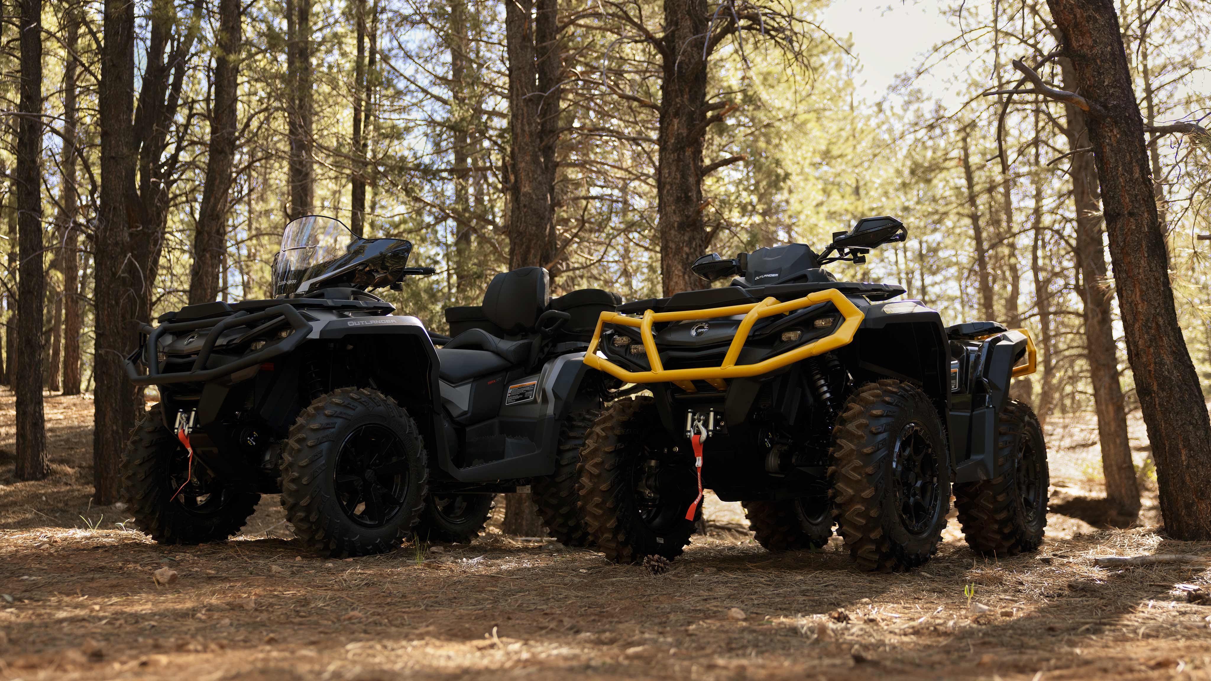 A Can-Am Outlander XT-P 100R and a Can-Am Outlander XT 850 parked in the forest. 