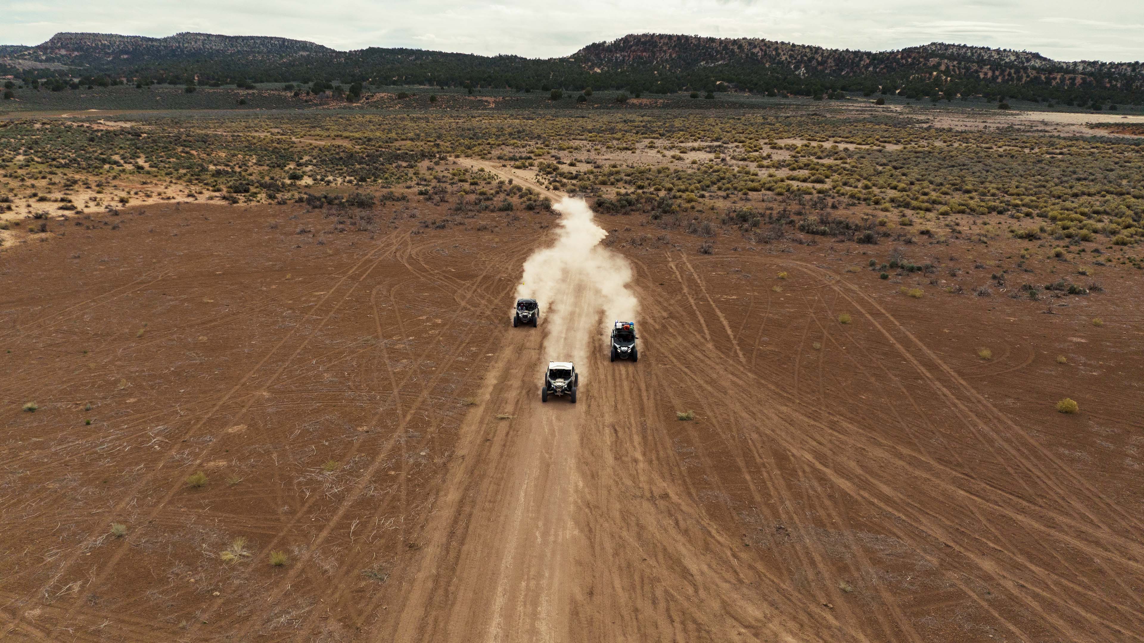 Arial view of three Can-Am side-by-sides on a path in a desert setting.