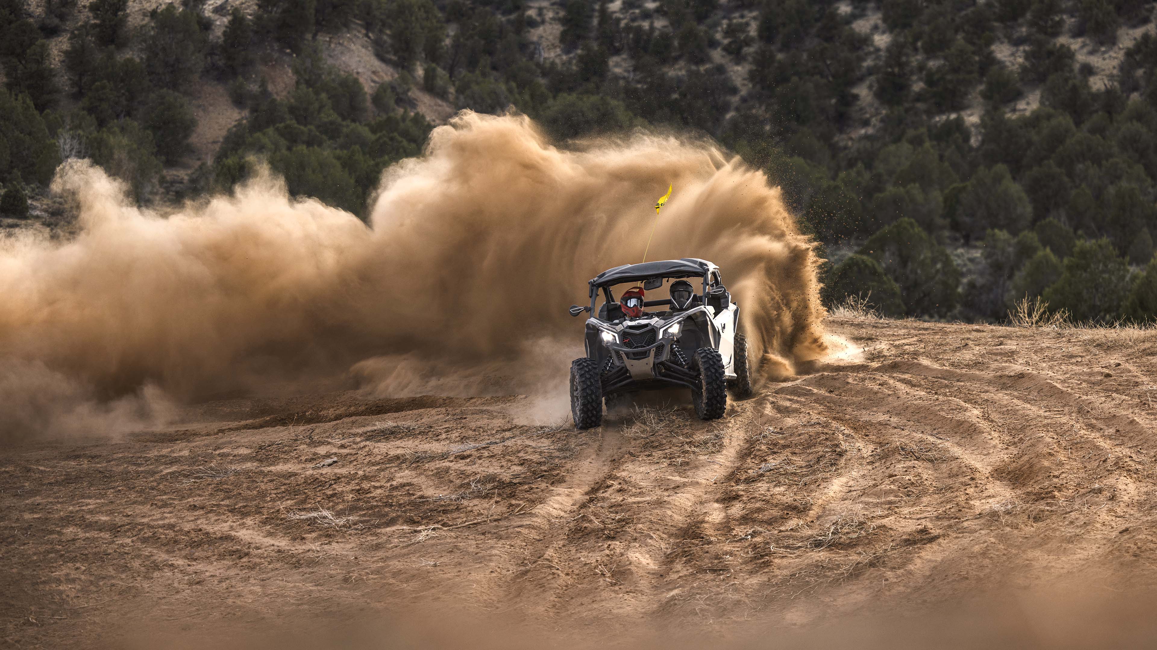 Front view of a Can-Am Maverick X3 X ds TURBO RR kicking up dust in a desert setting.