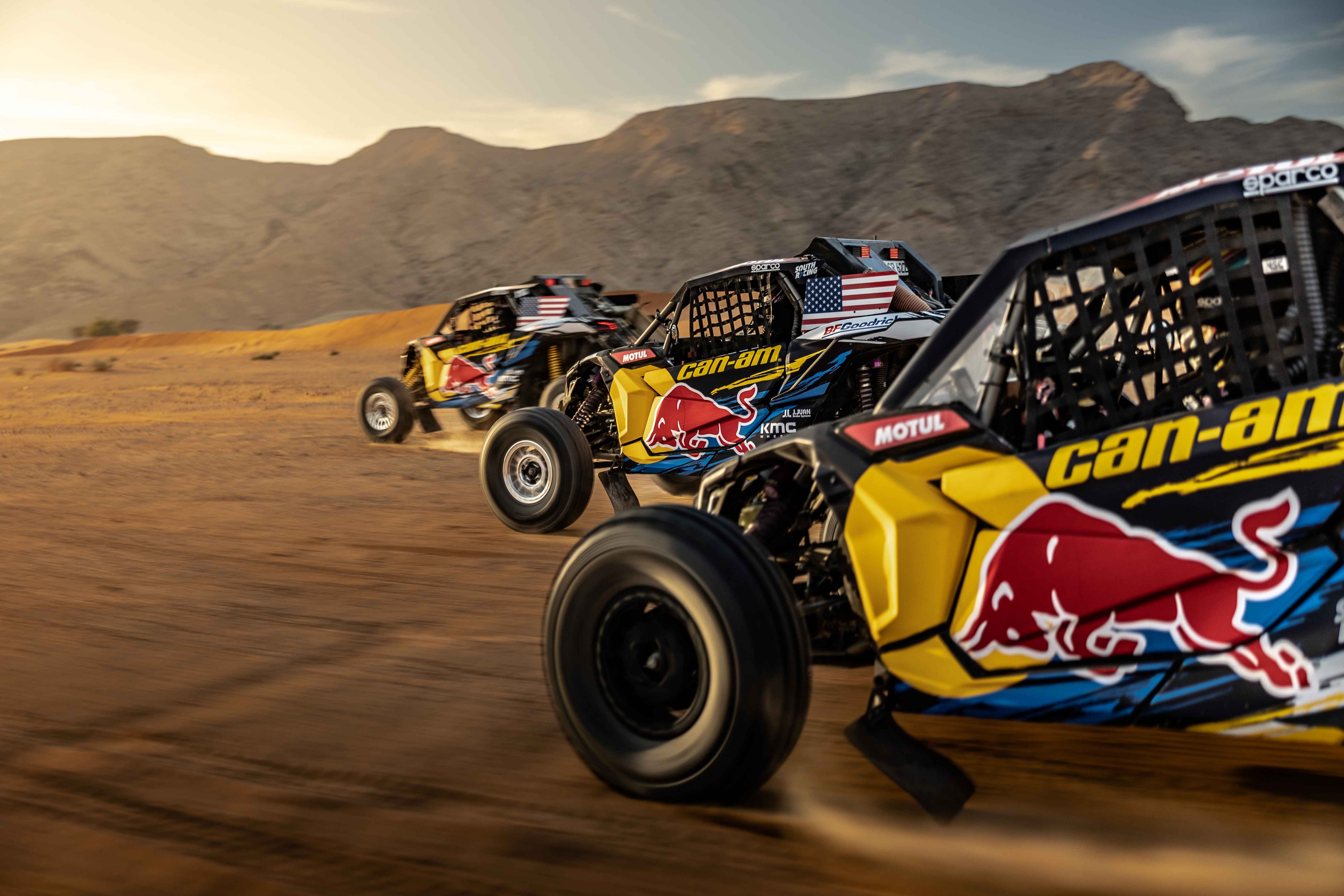 Three Red-Bull brand Can-Am Side-by-side vehicle racing at full speed