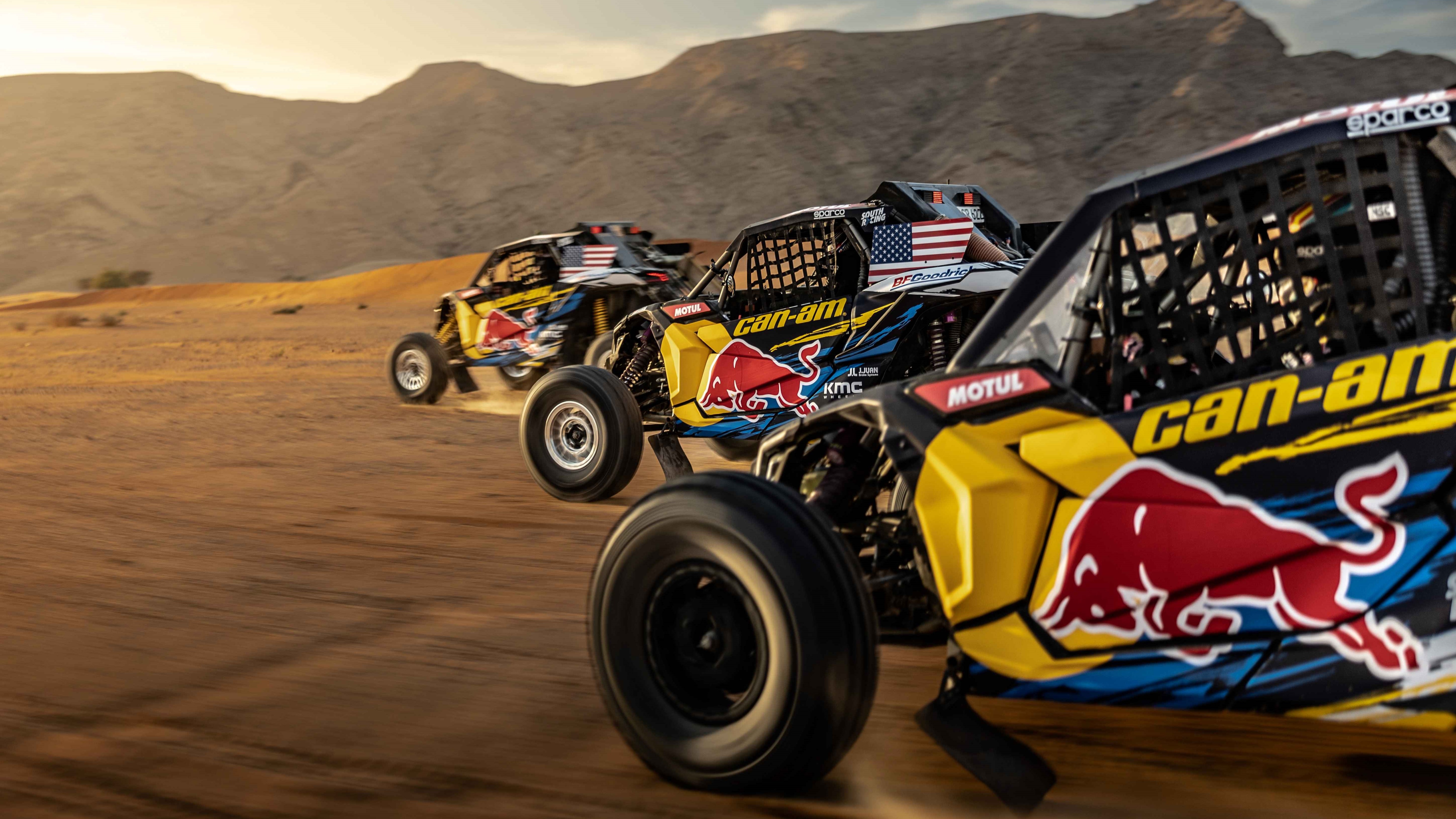 Three Red-Bull brand Can-Am Side-by-side vehicle racing at full speed