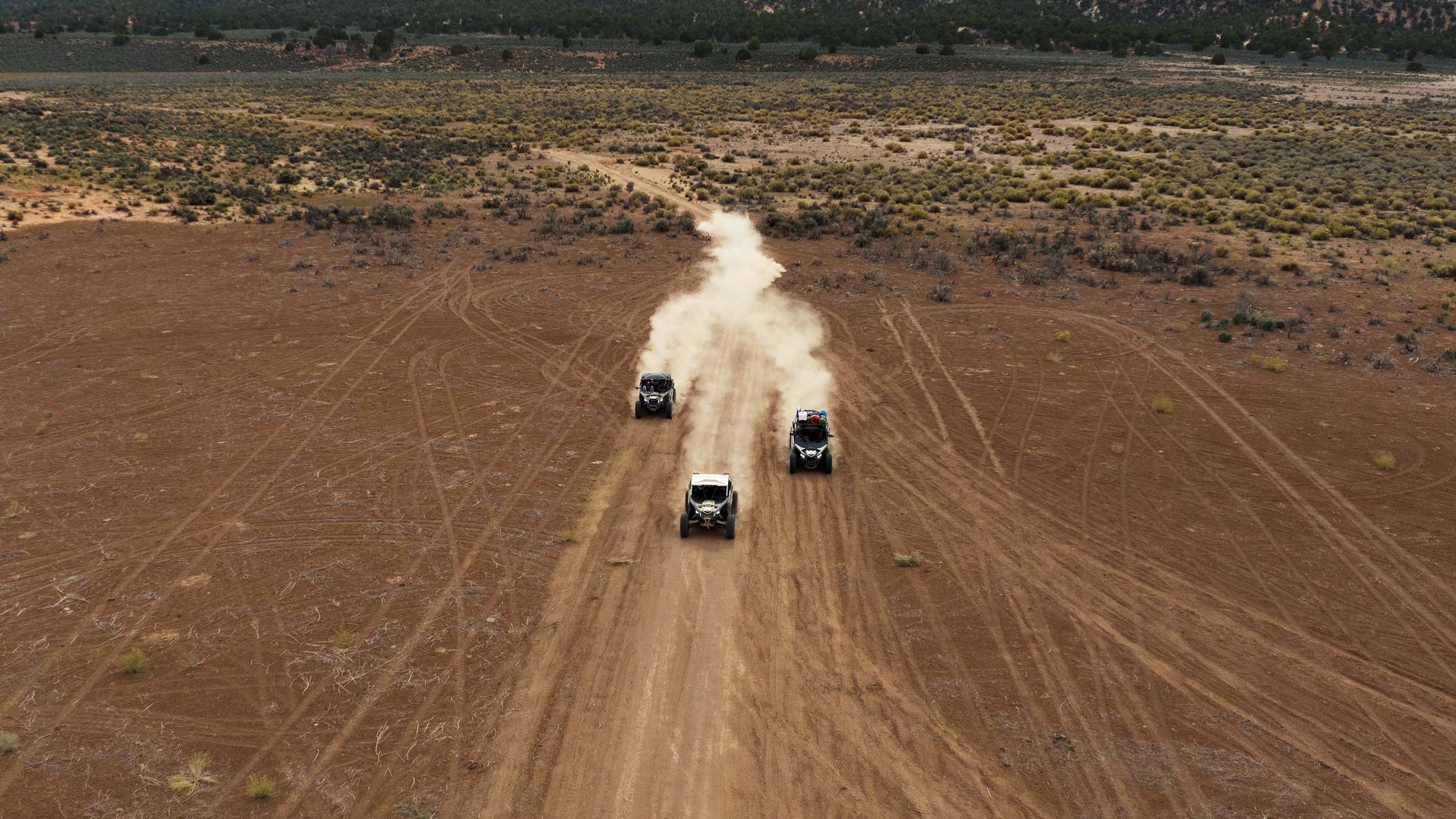 Arial view of three Can-Am side-by-sides on a path in a desert setting. 