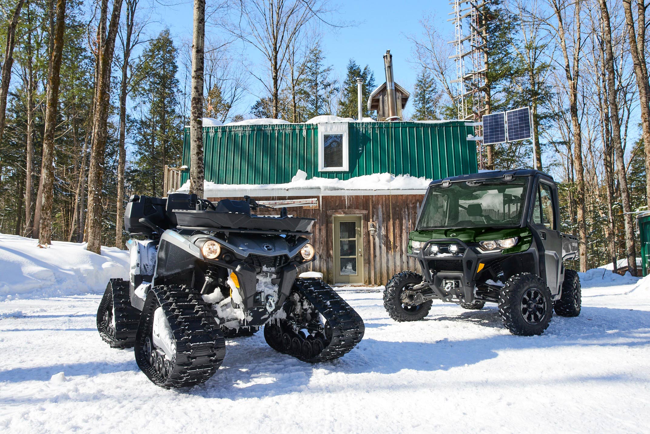 Can-Am Outlander och Traxter bredvid en stuga på vintern