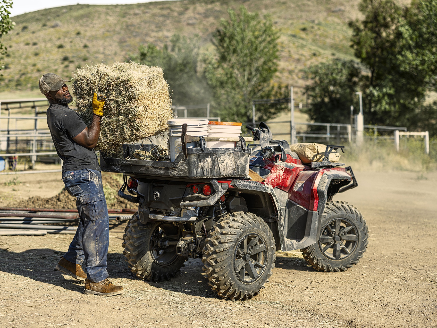 Man unloading a bale of hay from his Can-Am Outlander ATV