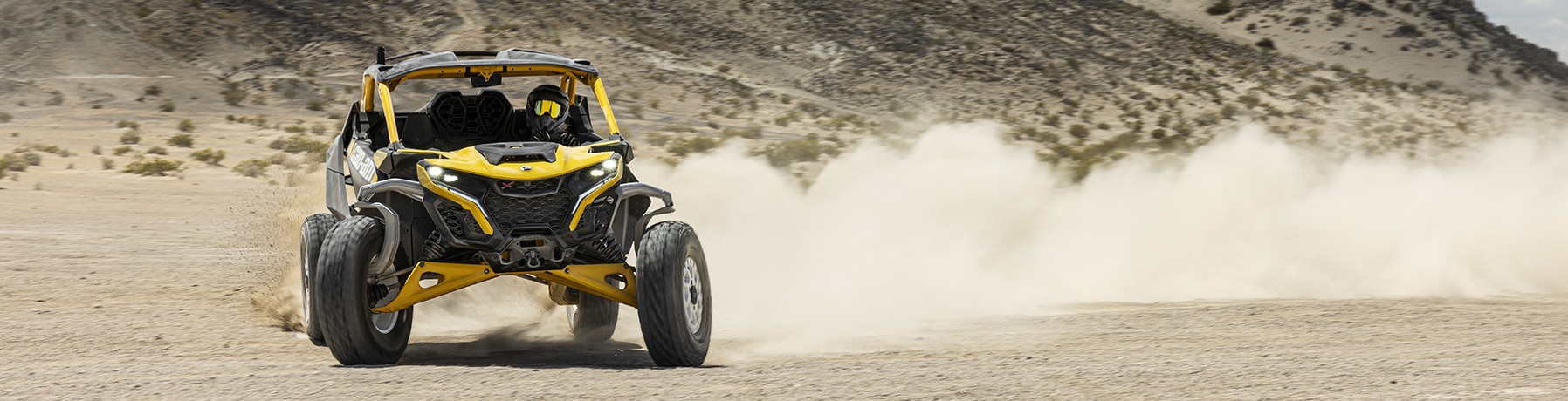 Een rijder rijdt met hoge snelheid op een Can-Am Maverick R in de woestijn
