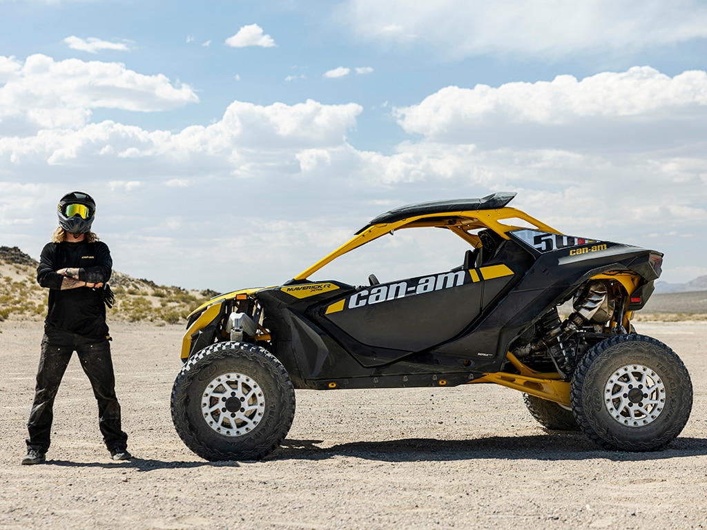 A rider next to his 2024 Can-Am Maverick R side-by-side vehicle