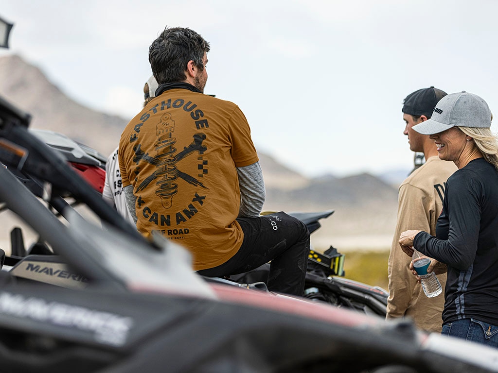 Four Can-Am riders taking a break alongside their SxS vehicles
