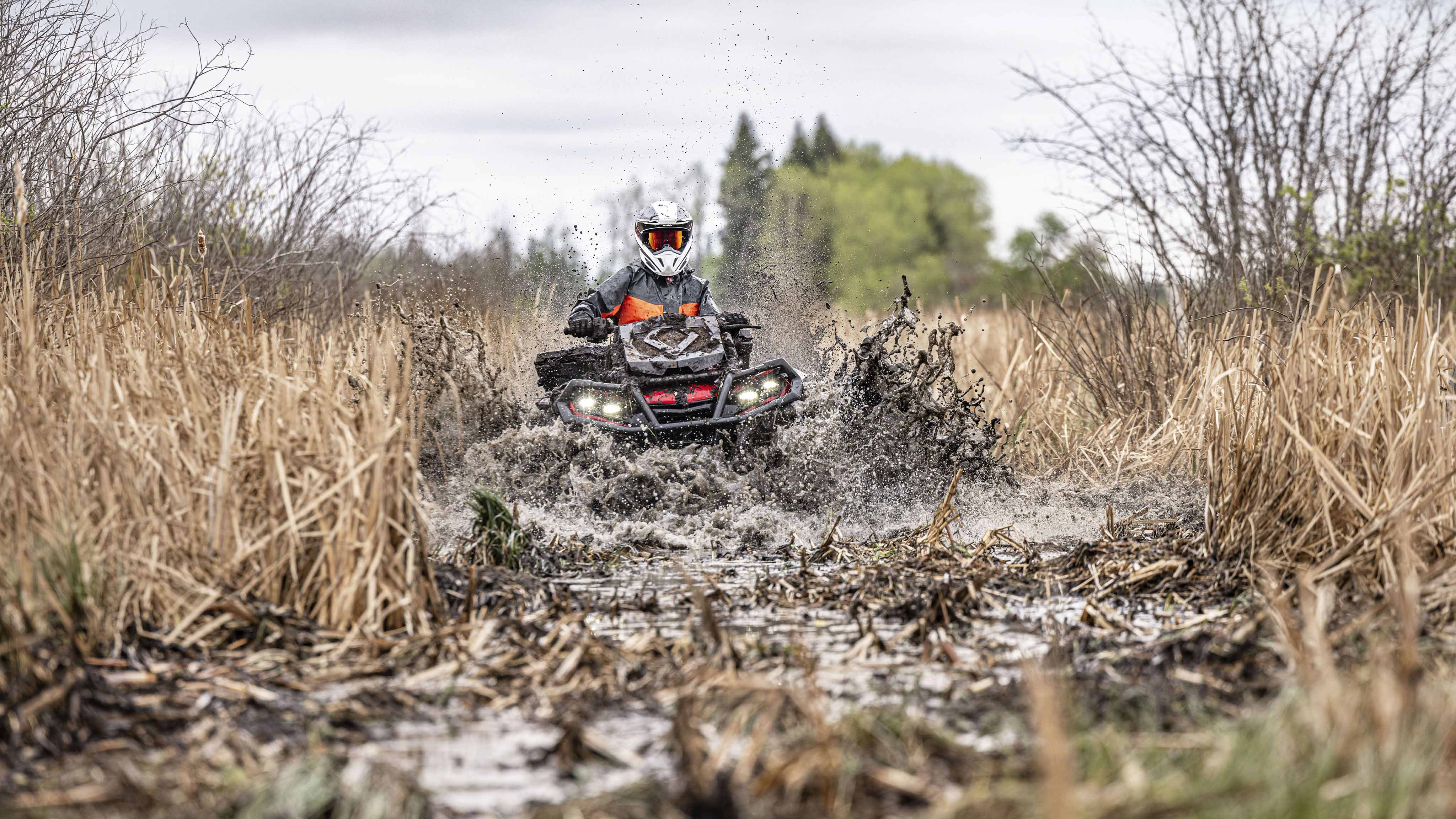 A Can-Am Outlander X MR ATV going through mud